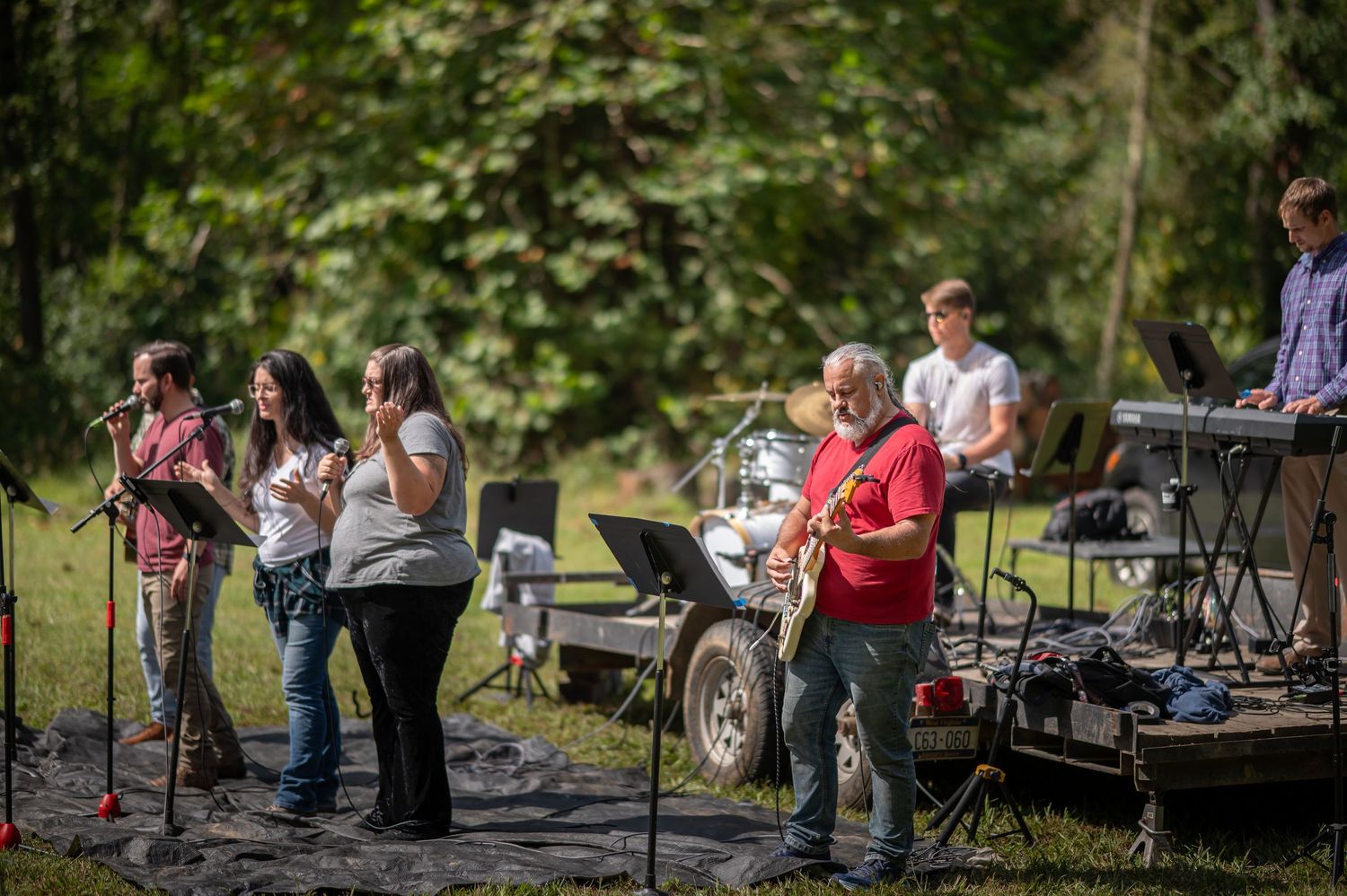 members of Crossroads' worship team lead singing at a Sunday morning church service outside in a large field