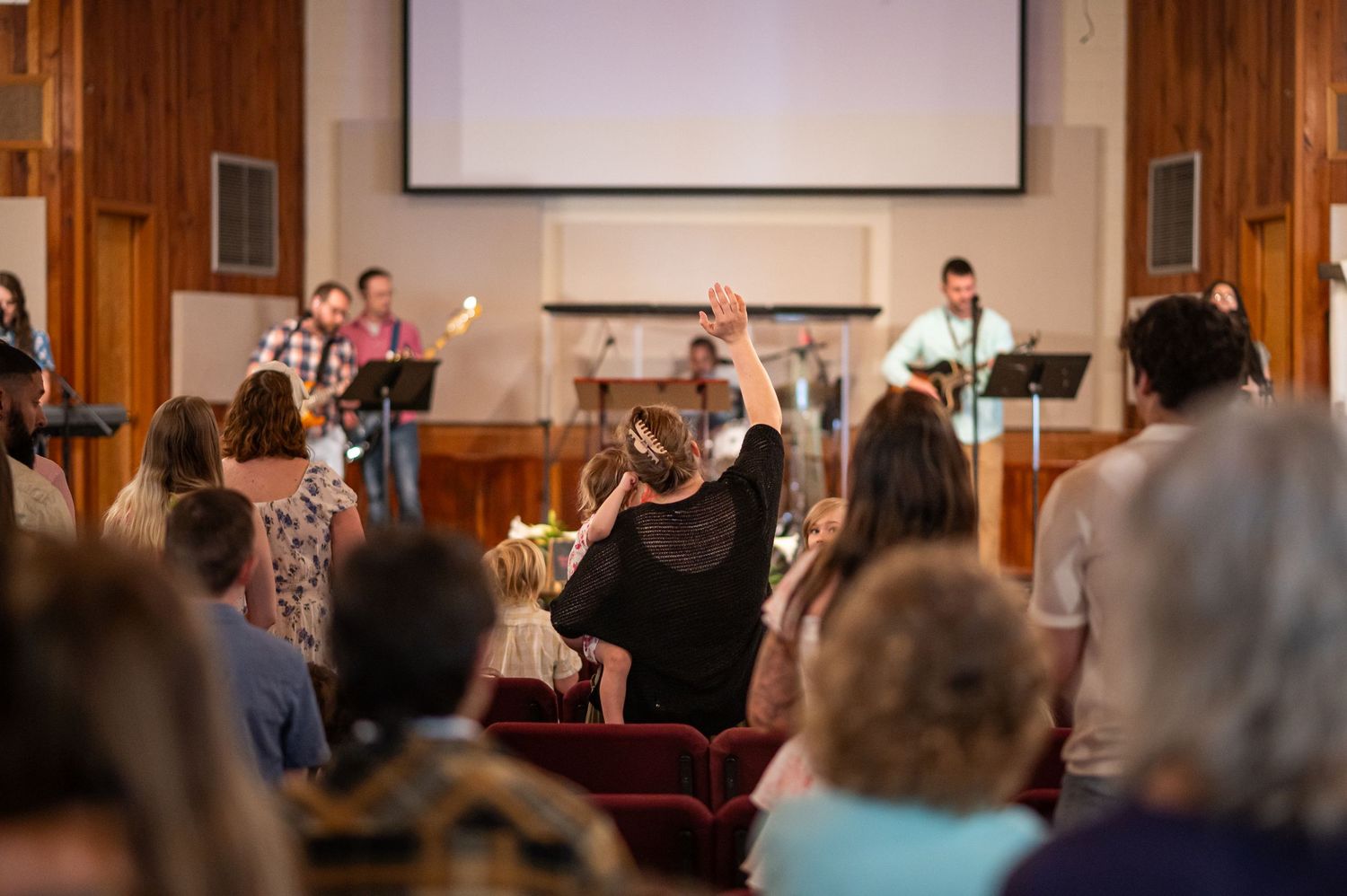 view from the rear of the church, over the heads of worshipers, of the worship team leading worship on the stage at Crossroads Morgantown