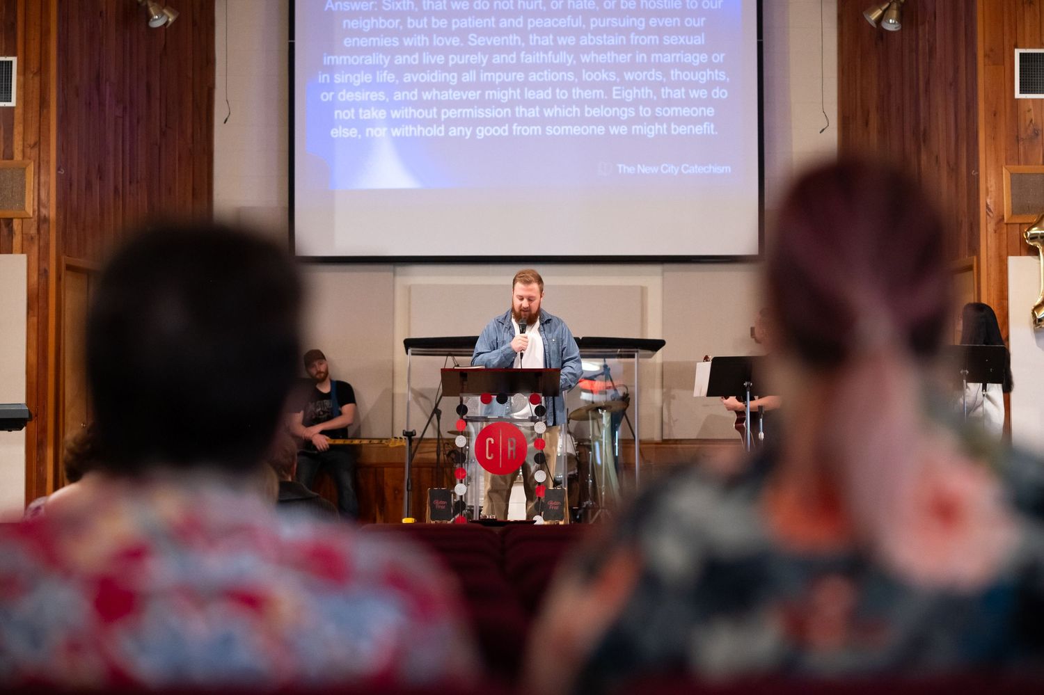 view from the seats in the auditorium of Crossroads Morgantown, of a church member standing at the pulpit giving announcements