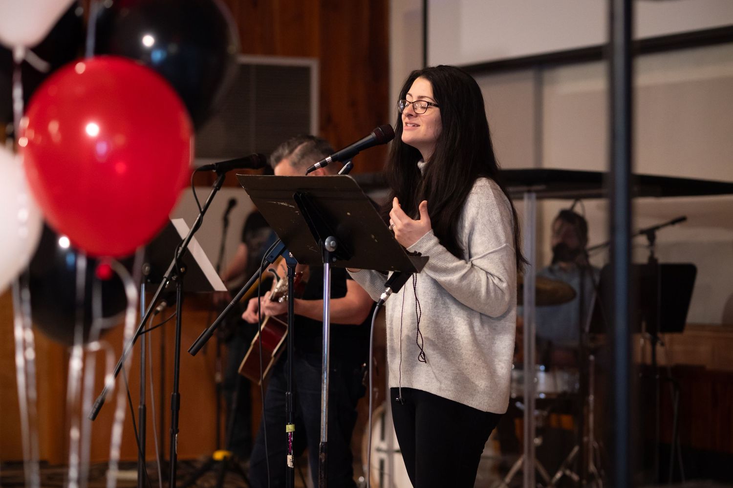 a woman stands on the stage singing with her eyes closed and hands raised in worship at Crossroads Church Morgantown, during Sunday service