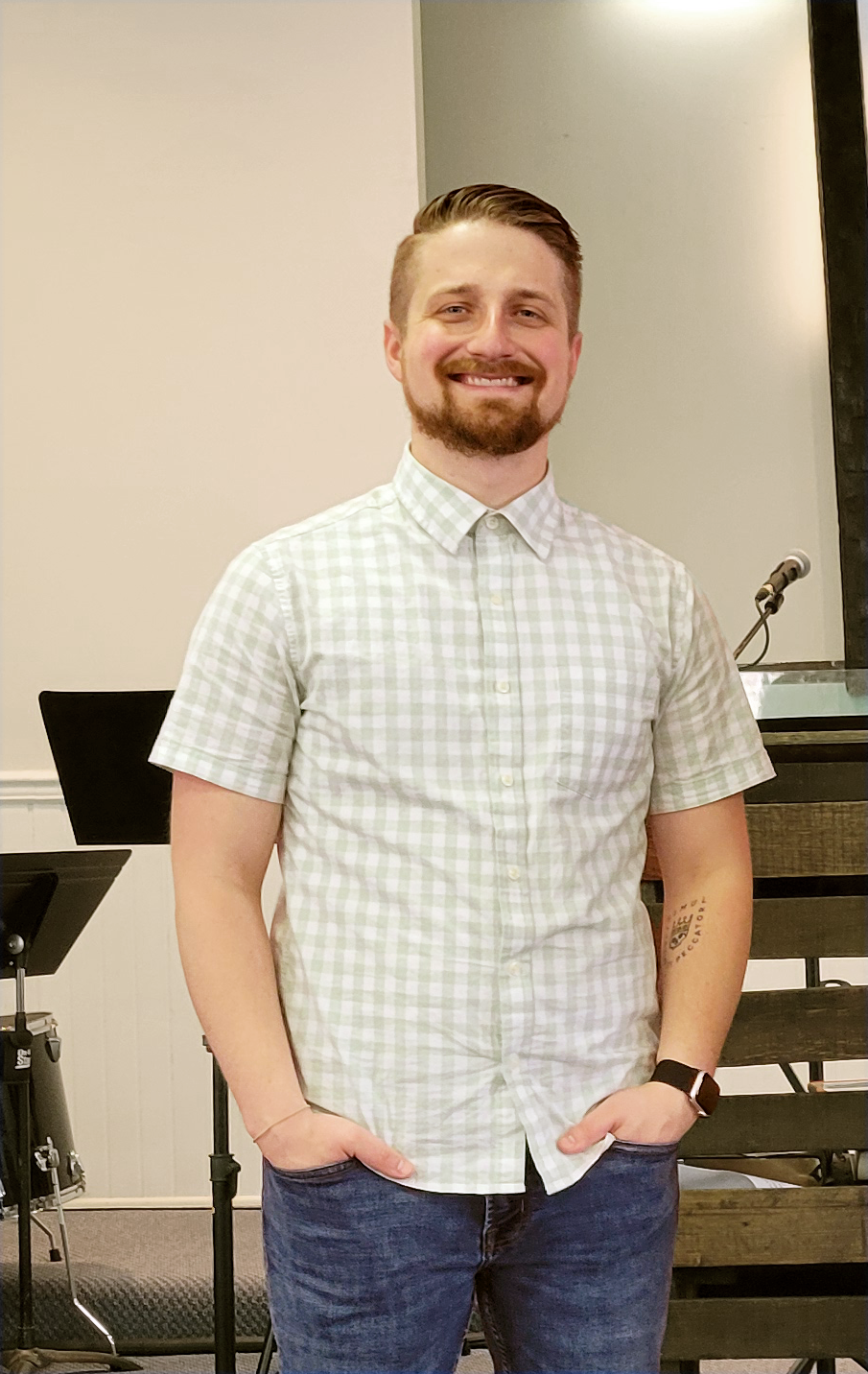 Pastor Brandon smiles for a picture with his hands in his pockets on the stage of Crossroads Fairmont after a Sunday morning church service