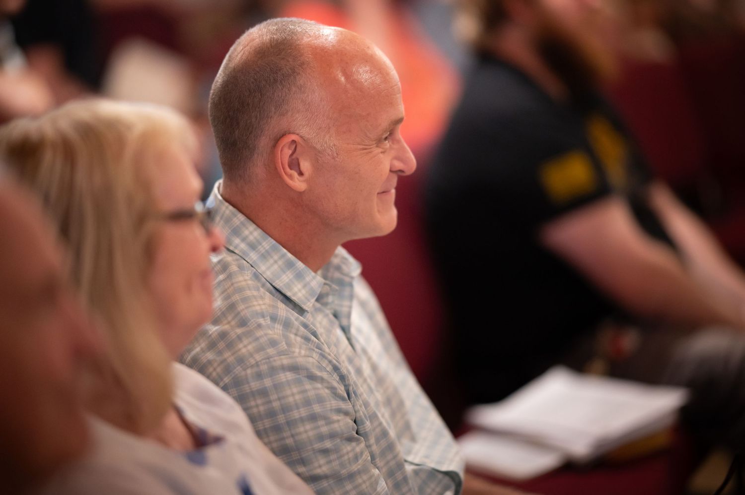 a man sits in the seats at a Crossroads Sunday gathering at the Morgantown location, smiling as he listens to the sermon;