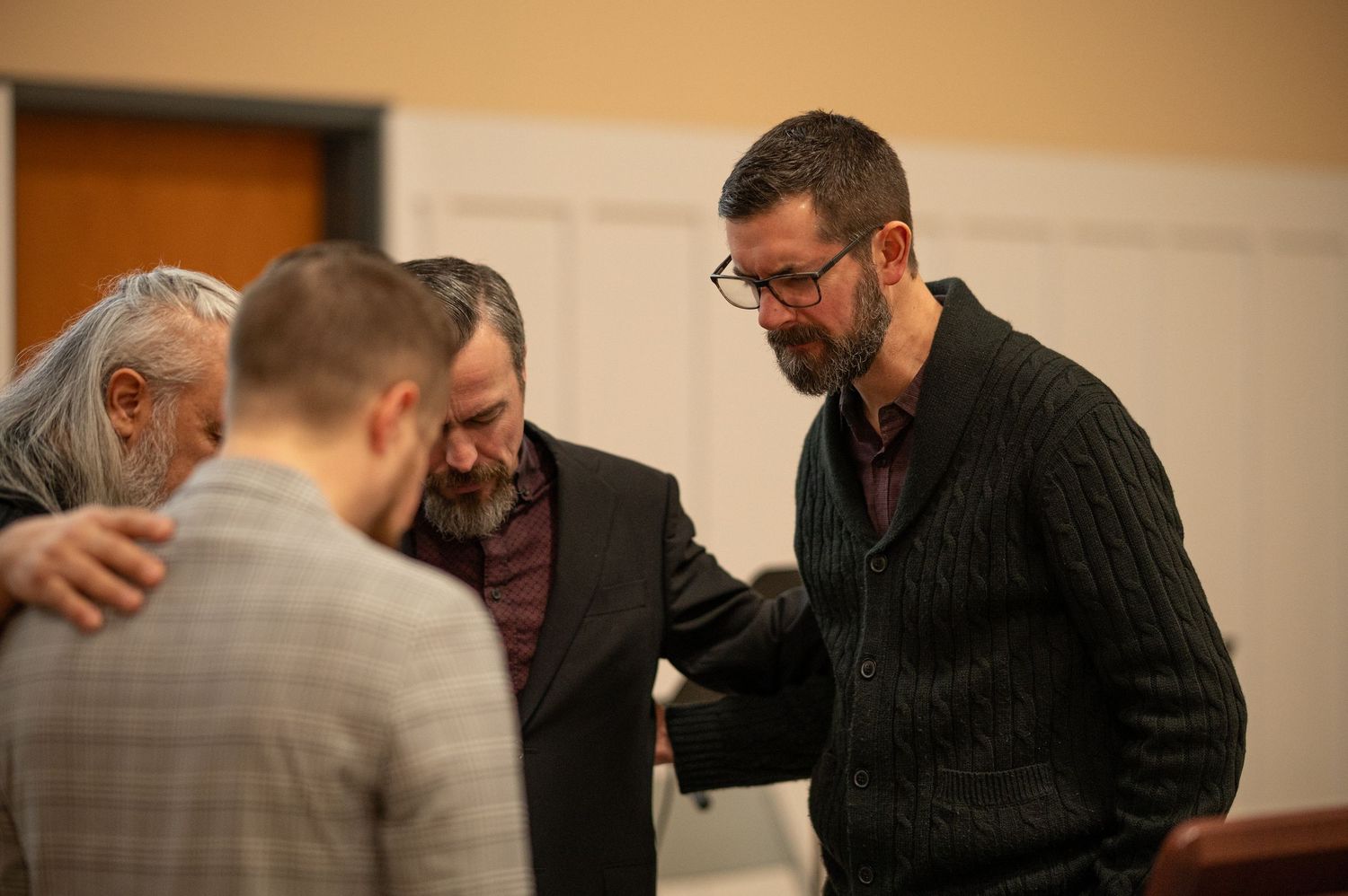 All four Crossroads pastors pray together with arms around each others shoulders at the start of a church event