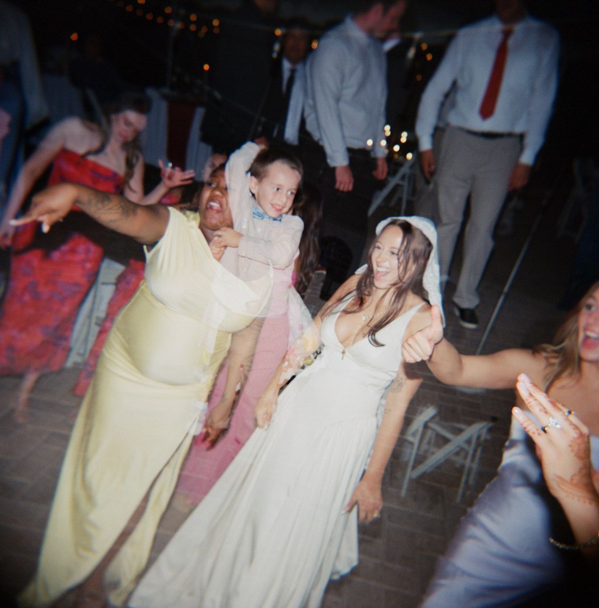 Bride and guests dancing joyfully at a wedding reception, with a double exposure on film of a child and groomsmen dancing together.