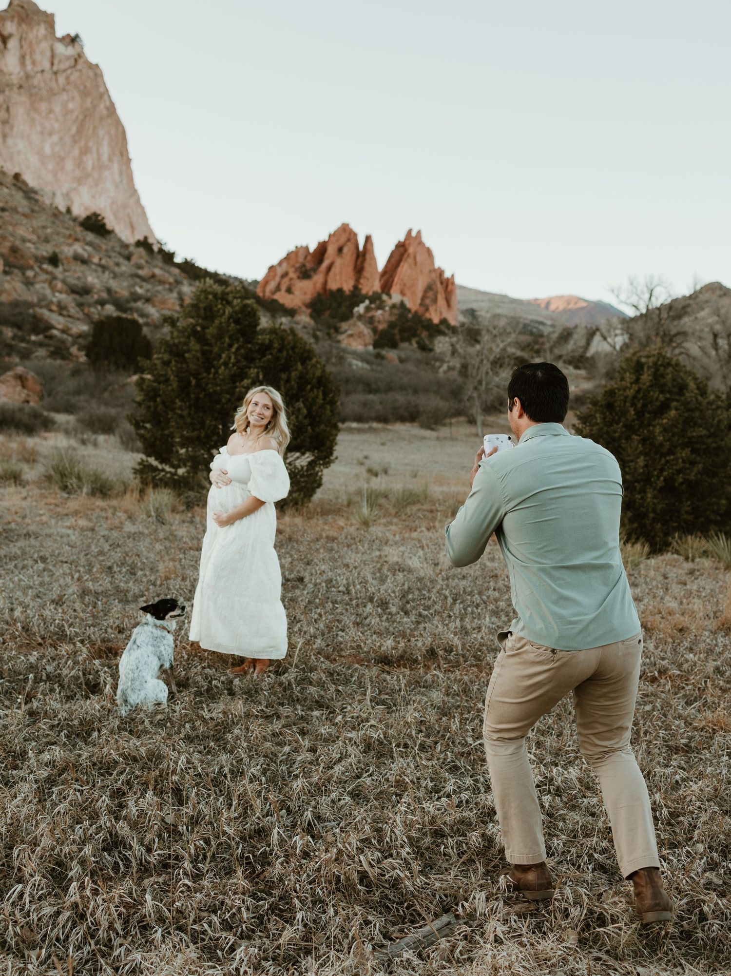 Professional photographer captures a photo session at Garden of the Gods with red rock formations in the background at sunset.