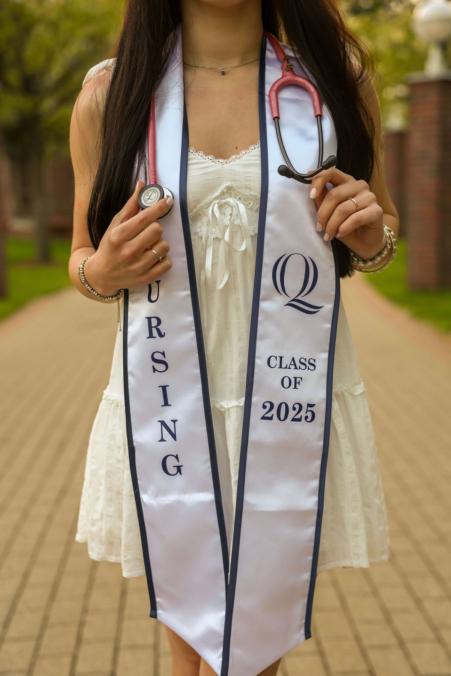 Nursing Class of 2025 graduation stole with Quinnipiac University logo held by graduate with pink stethoscope.