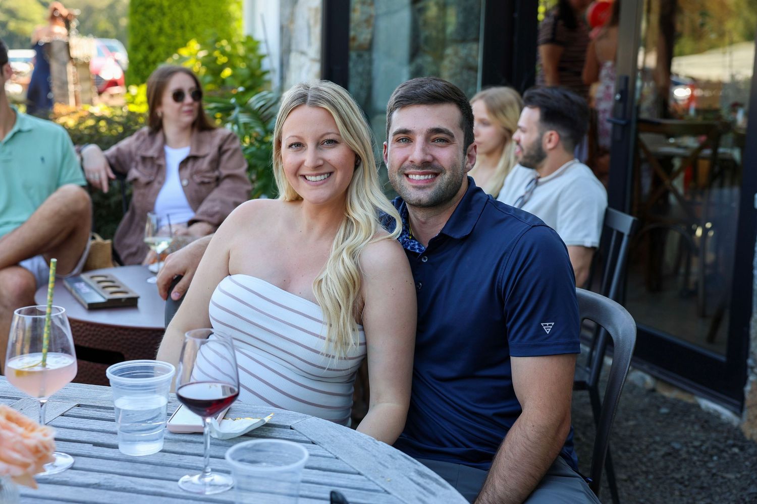 Couple smiling together at outdoor restaurant patio table with wine glasses.