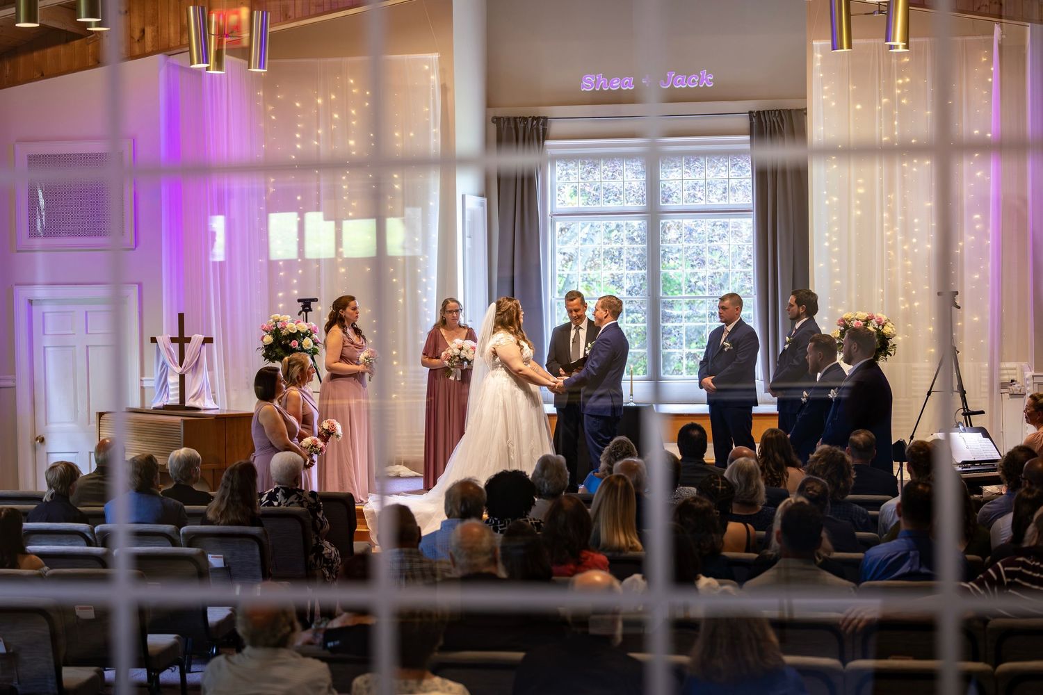 Wide angle view of elegant indoor wedding ceremony with fairy lights and floral arrangements.
