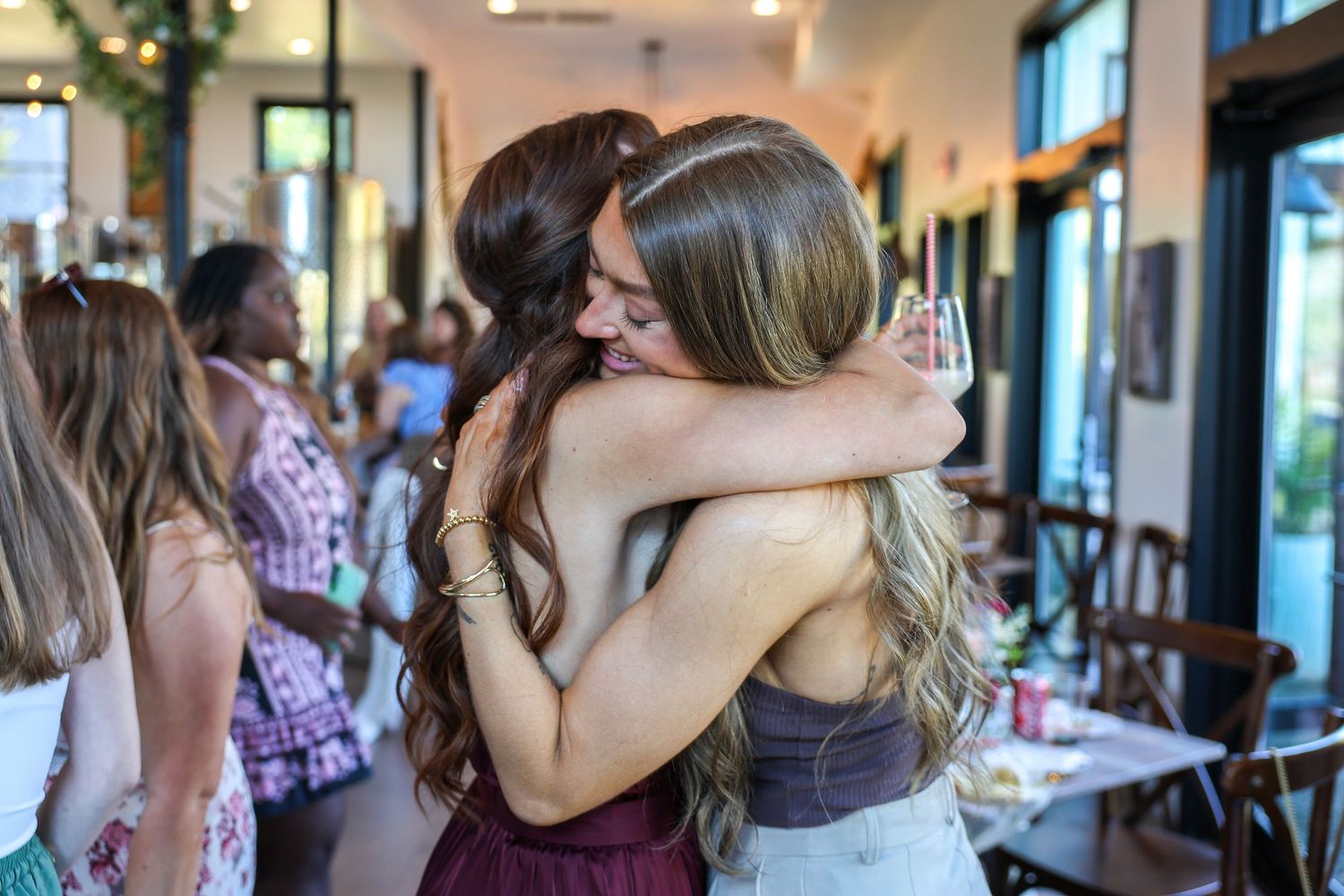Two women sharing warm embrace at indoor celebration event.