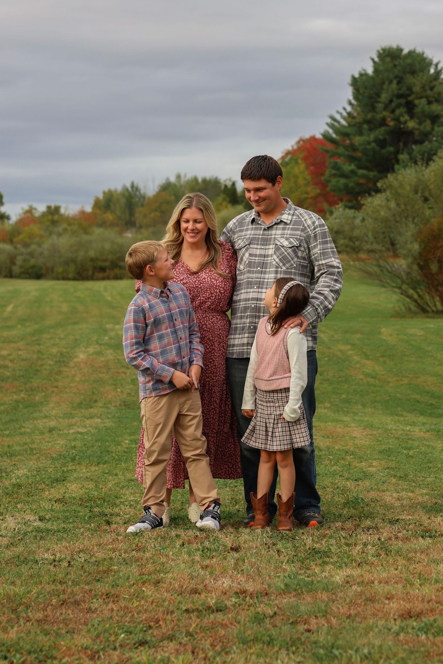 Pregnant mother and father pose with two children in autumn outdoor family portrait session.