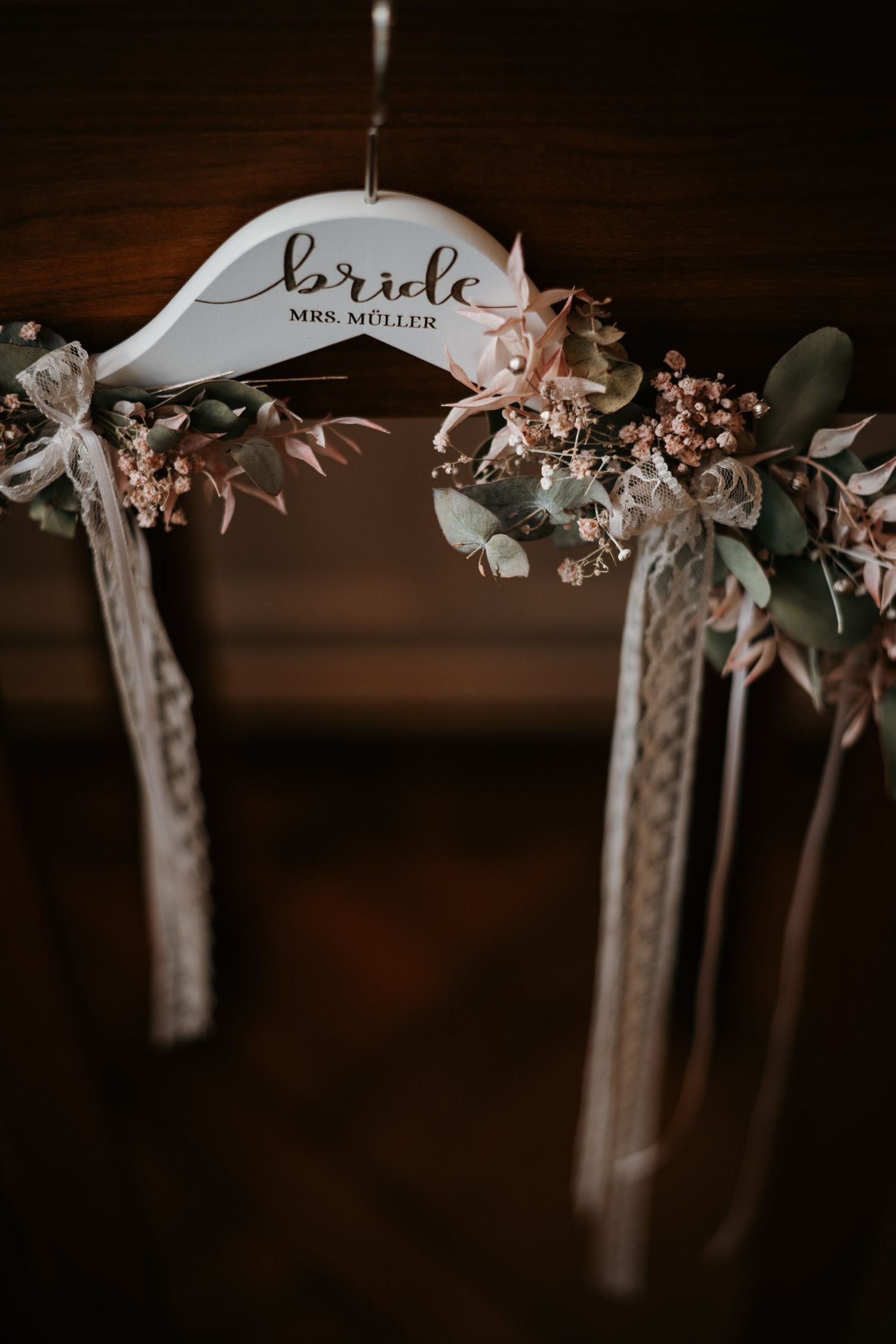 Decorative bride hanger reading Mrs. Muller adorned with eucalyptus and pink floral accents.