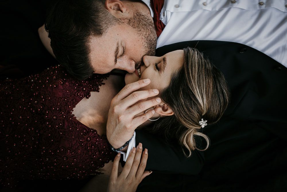 Romantic couple lying down sharing an intimate almost-kiss moment, hands intertwined tenderly.