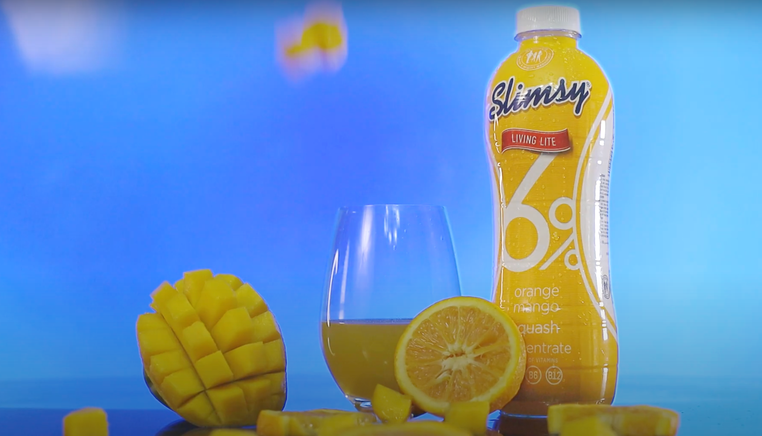 Slimsy mango lemon flavored drink bottle displayed with fresh mango and citrus slices.
