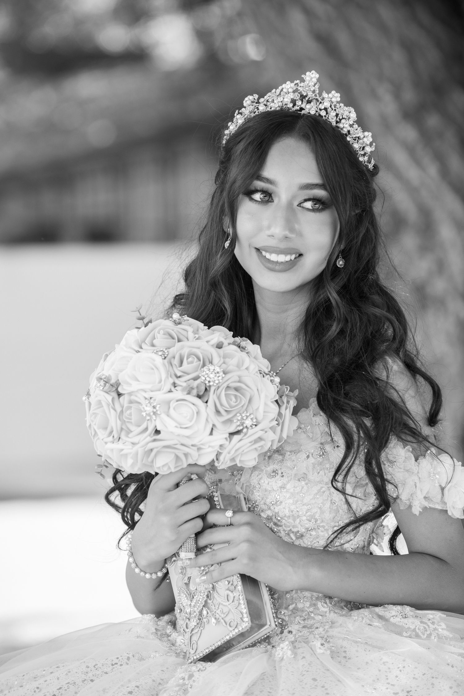 Black and white portrait of a bride in a ballgown wedding dress with tiara holding a rose bouquet.