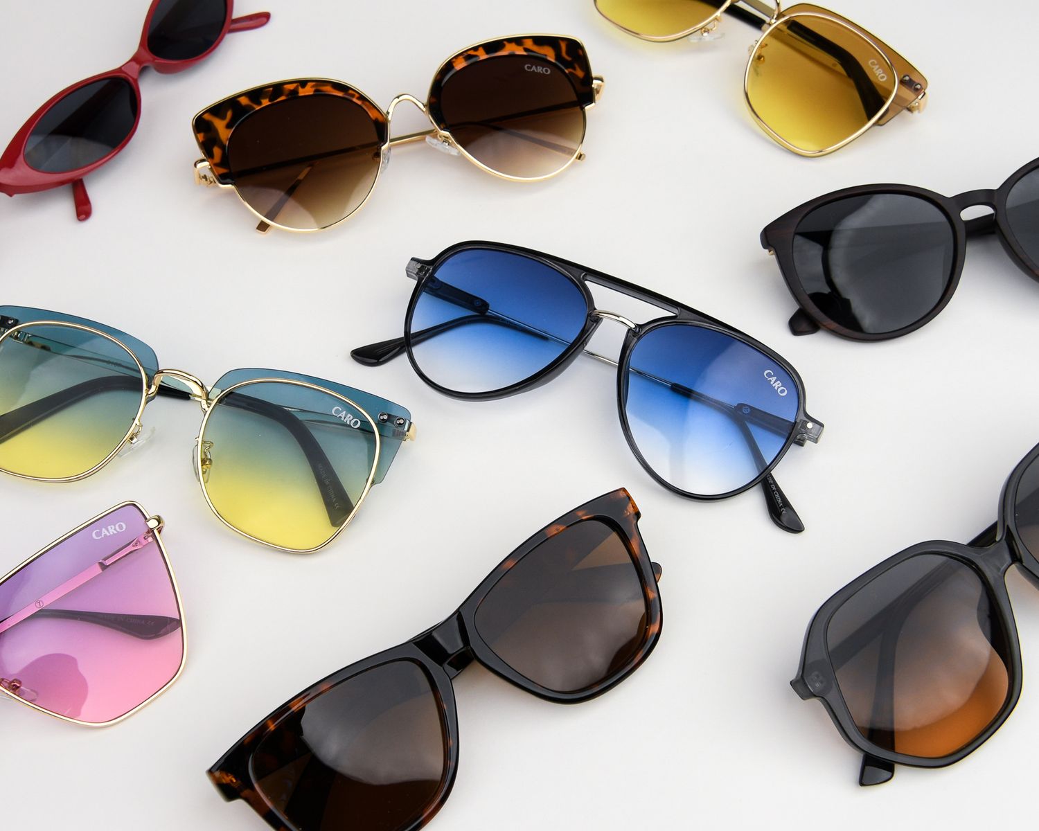 Stylish collection of trendy sunglasses in various colors and frames laid out on white background.