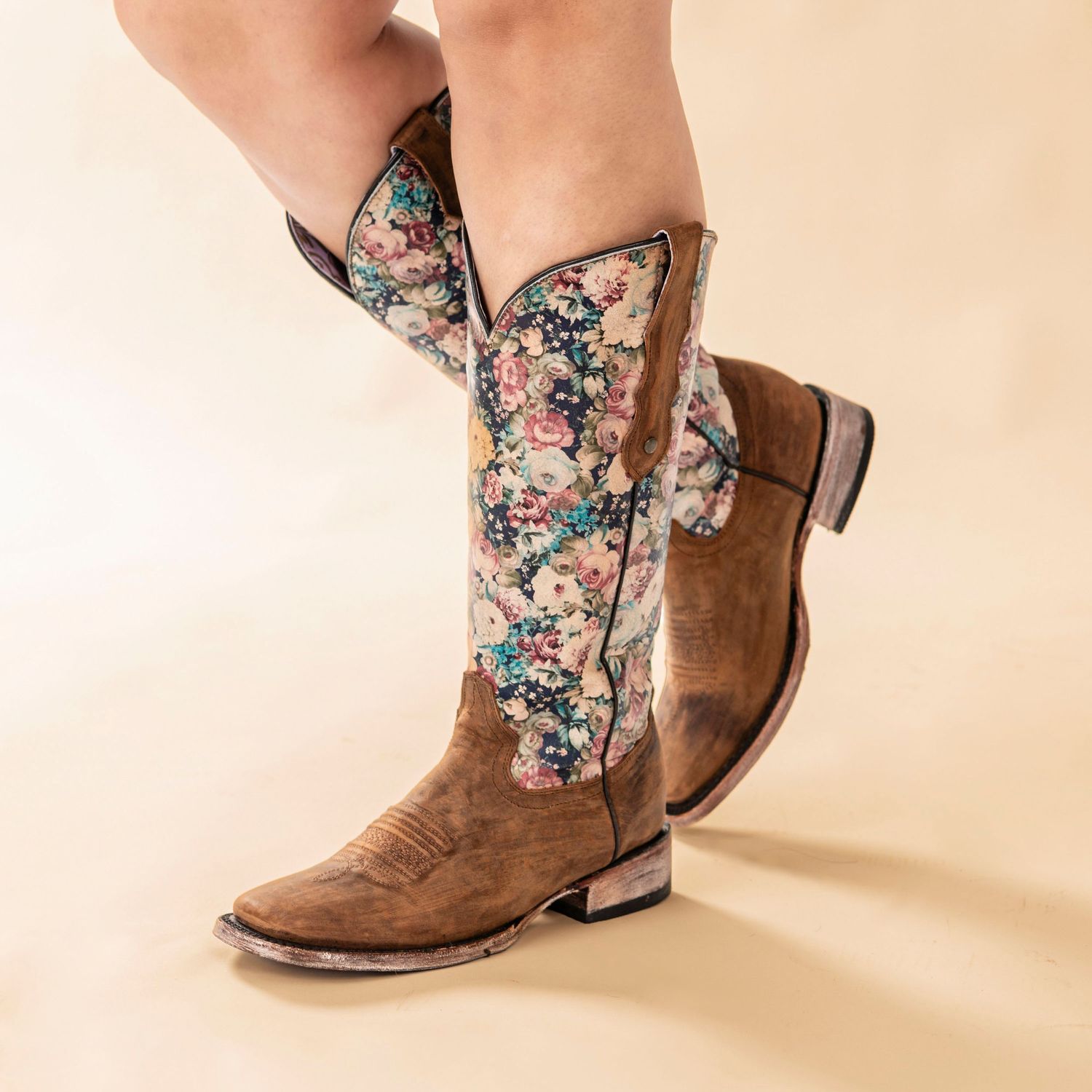 Brown leather cowboy boots with floral pattern detail and low heel shown against neutral background.