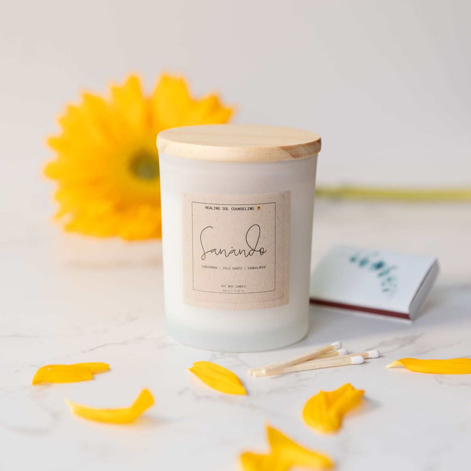 Minimalist scented candle with yellow flower petals and white knit texture.