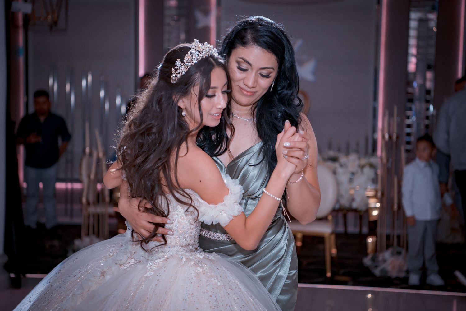 Touching moment between two elegantly dressed figures dancing together at an event.