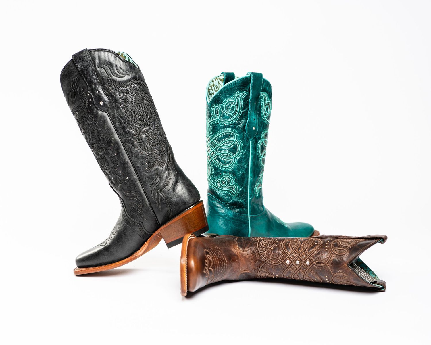 Three western cowboy boots in black, turquoise and brown leather arranged artistically.