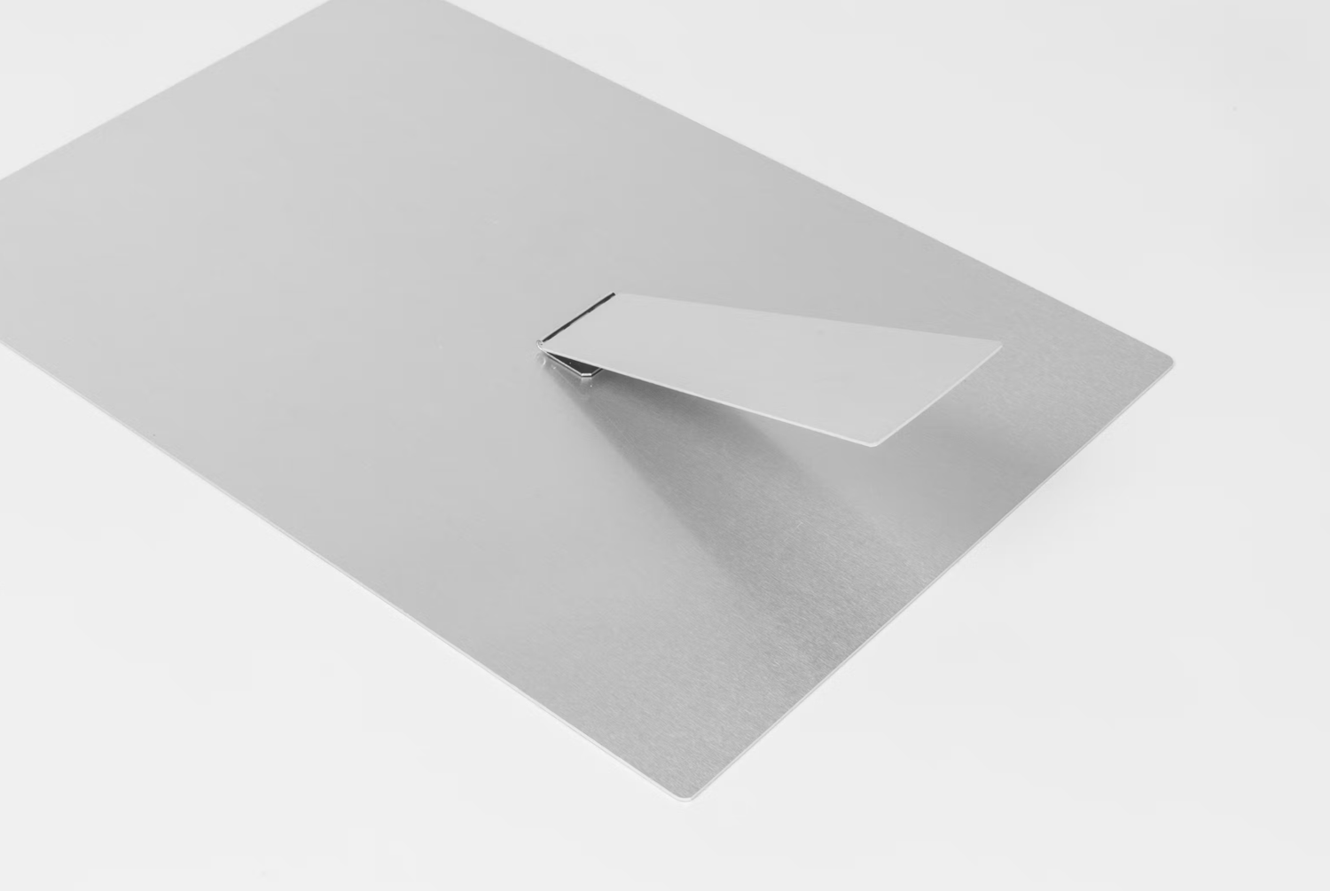 A flat gray metal sheet with a small folded flap raised at an angle on a white surface.