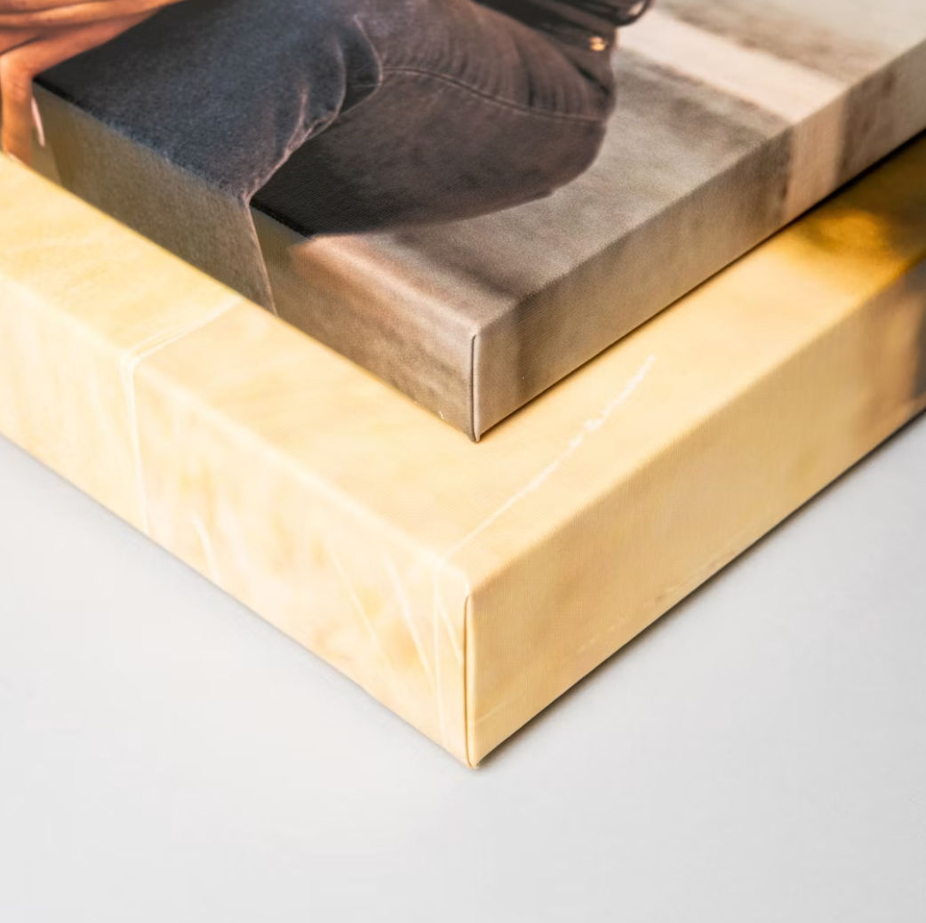 Two stacked canvas prints showing a person sitting, with a blank yellow canvas displayed beneath a photo canvas print.