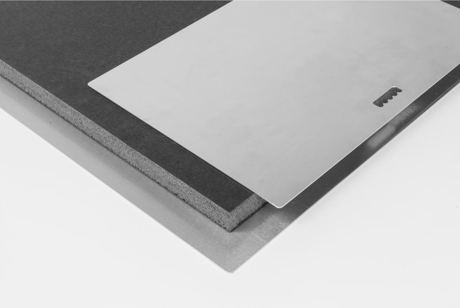 Stack of layered gray foam boards with a smooth silver top sheet, showcasing material thickness and texture.