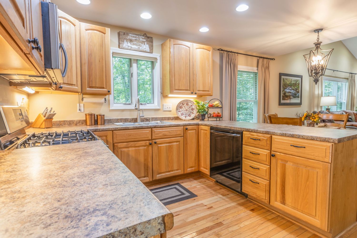Modern kitchen with honey oak cabinets, stainless steel appliances, and a wraparound granite countertop with bar seating.