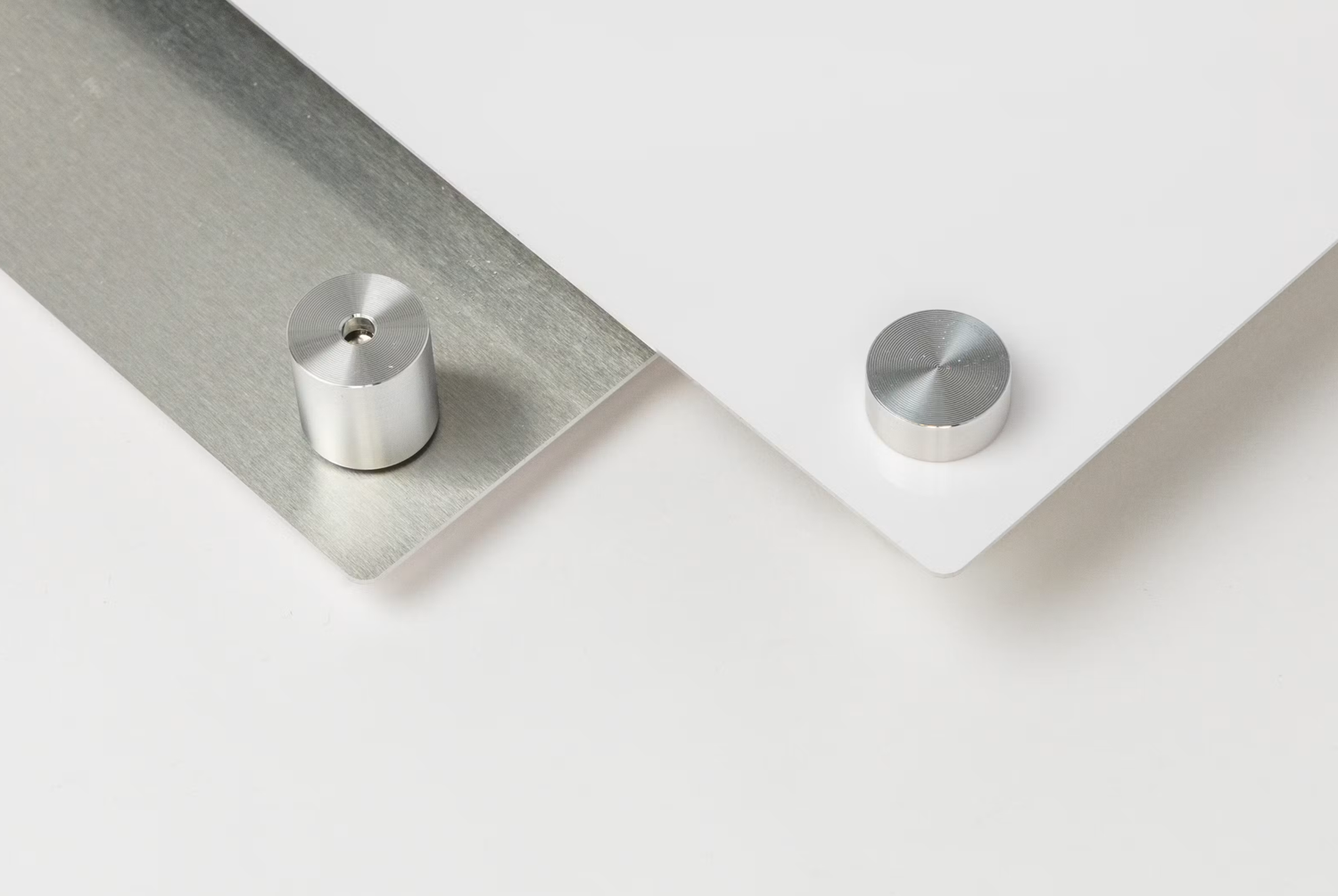 Two silver aluminum standoff screws displayed on white and metallic surfaces, showcasing modern minimalist hardware design.