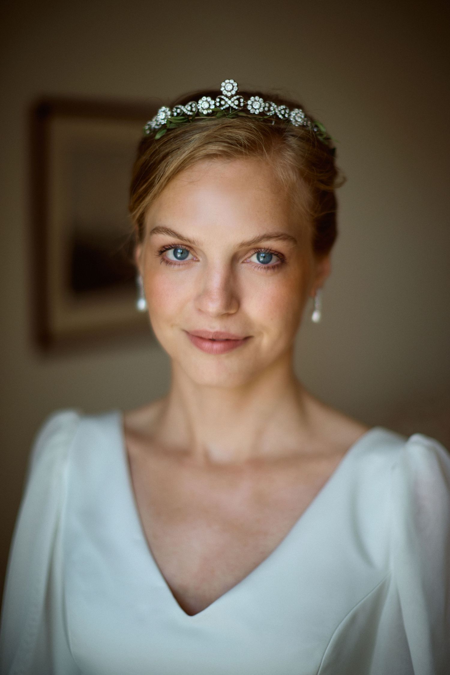 Roayl bride looking at the camera weding a family tiara and pear earrings. Elegant Royal weddig photography.