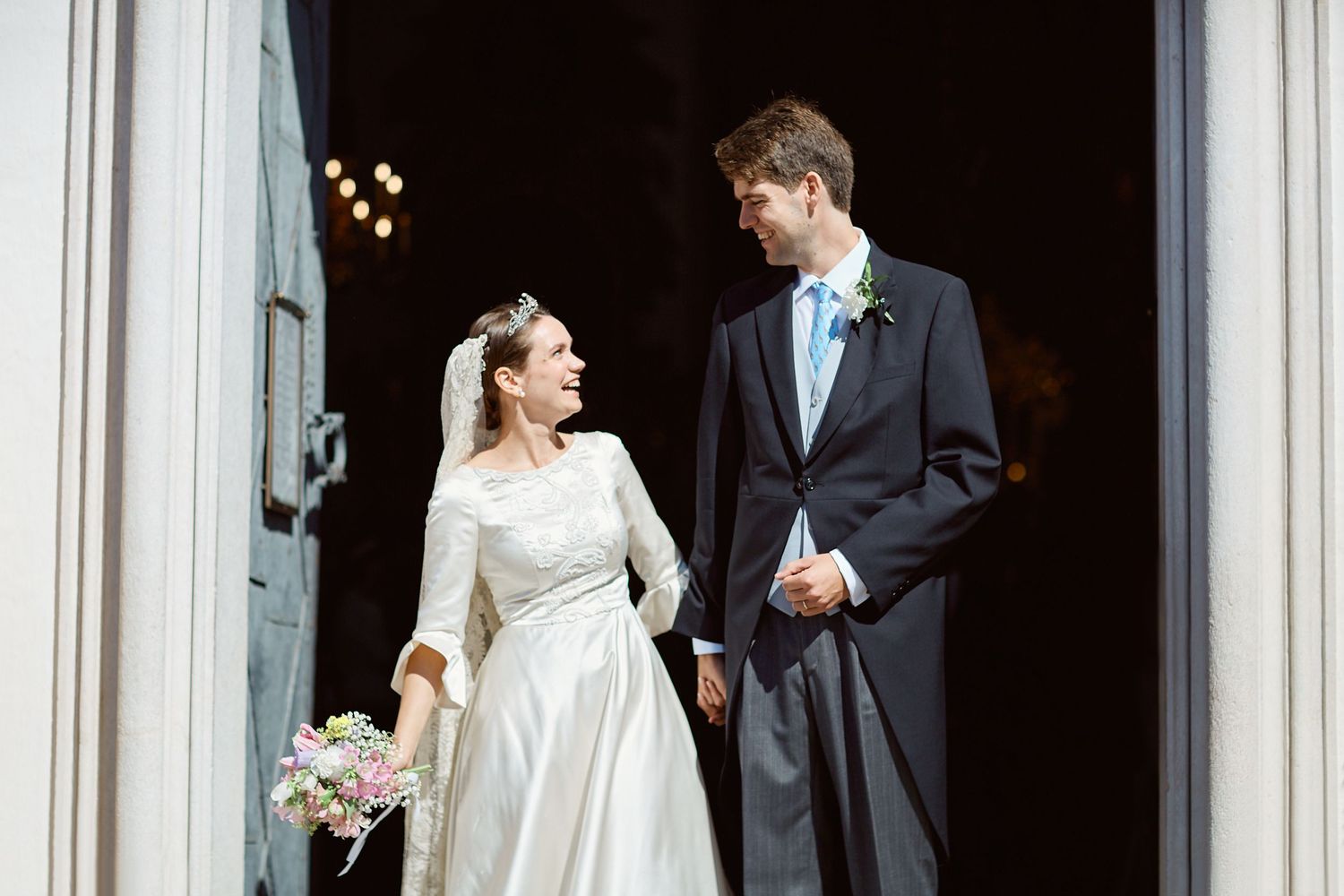 Royal couple exiting the church after a wedding. Smiling at each other.