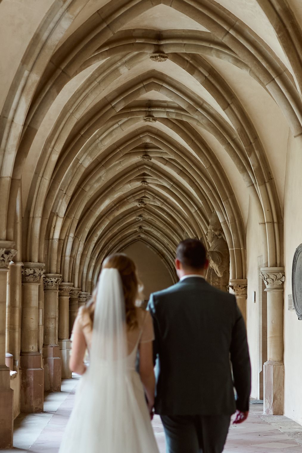 Just married couple walking through medieval cathedral. Catholic wedding photography Europe.