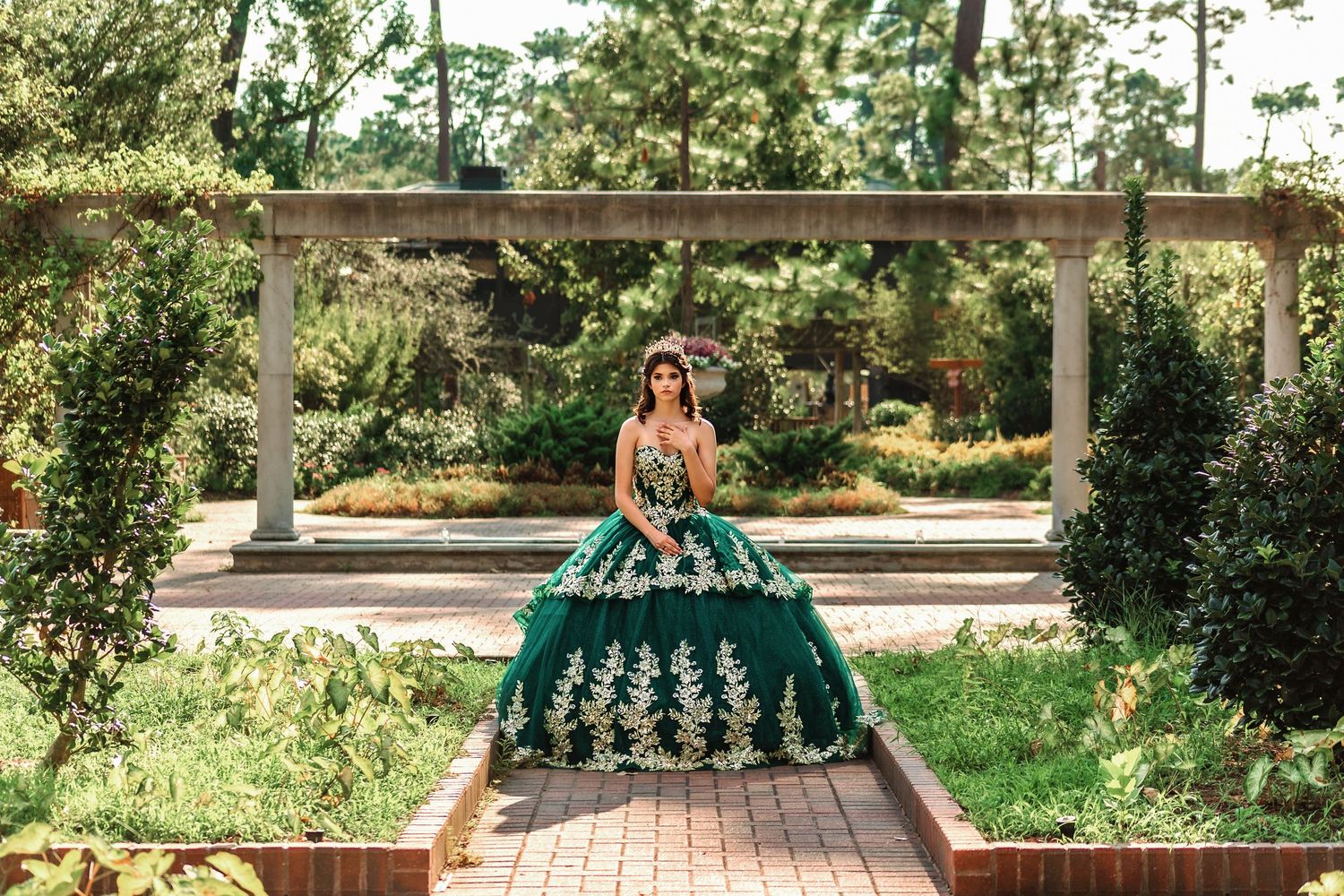 Beautiful young girl in green and gold Quinceañera dress posing outdoors
