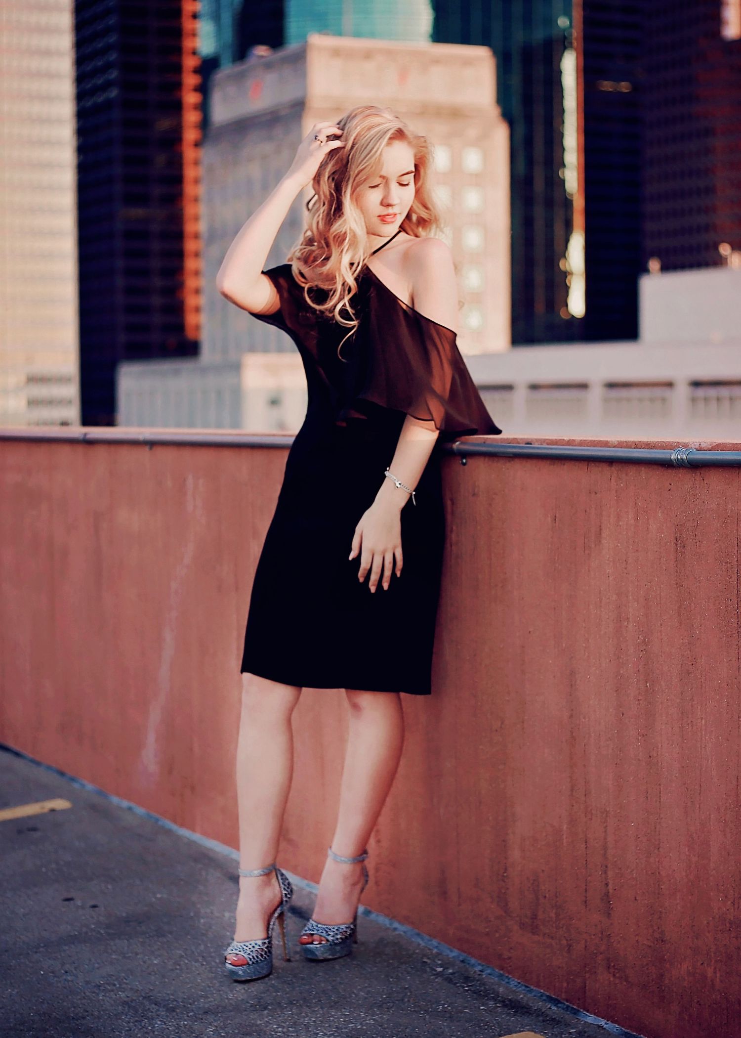 Senior girl with golden blonde hair posing with downtown skyline backdrop