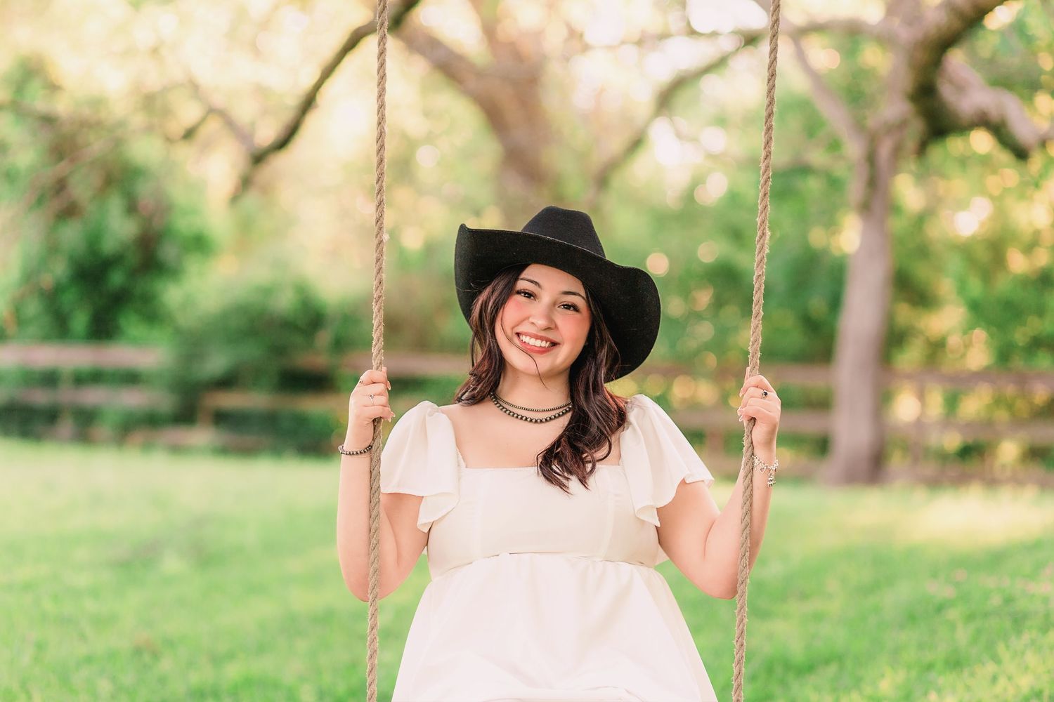 Young woman dressed in cowgirl outfit swinging on rope swing