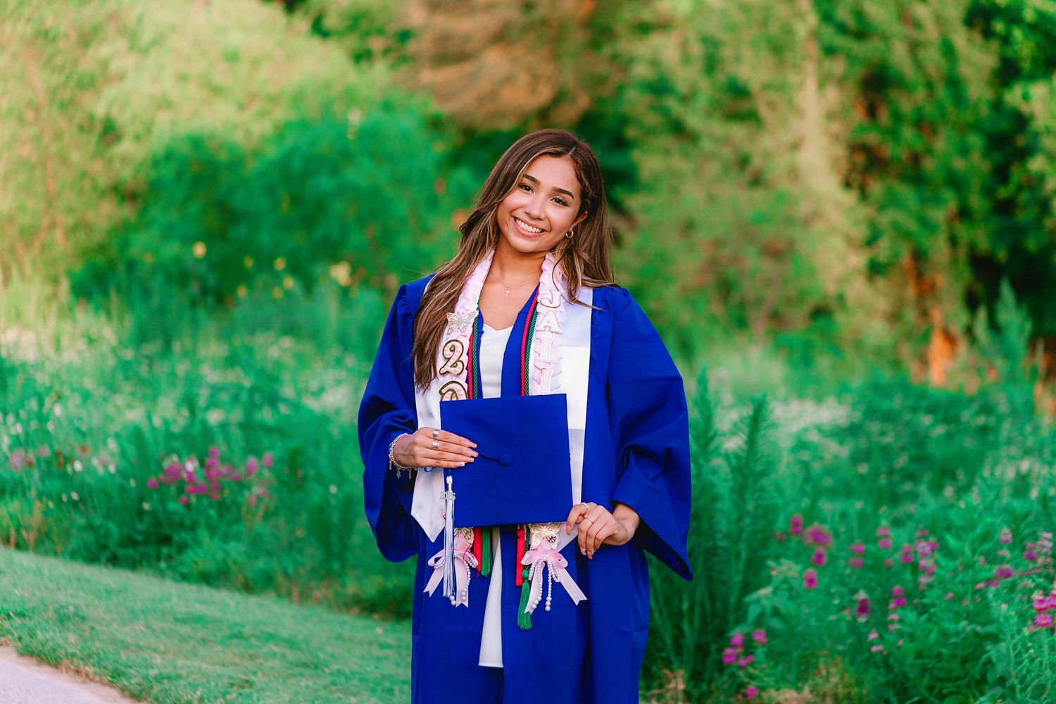 Senior girl in blue graduation attire on natural background