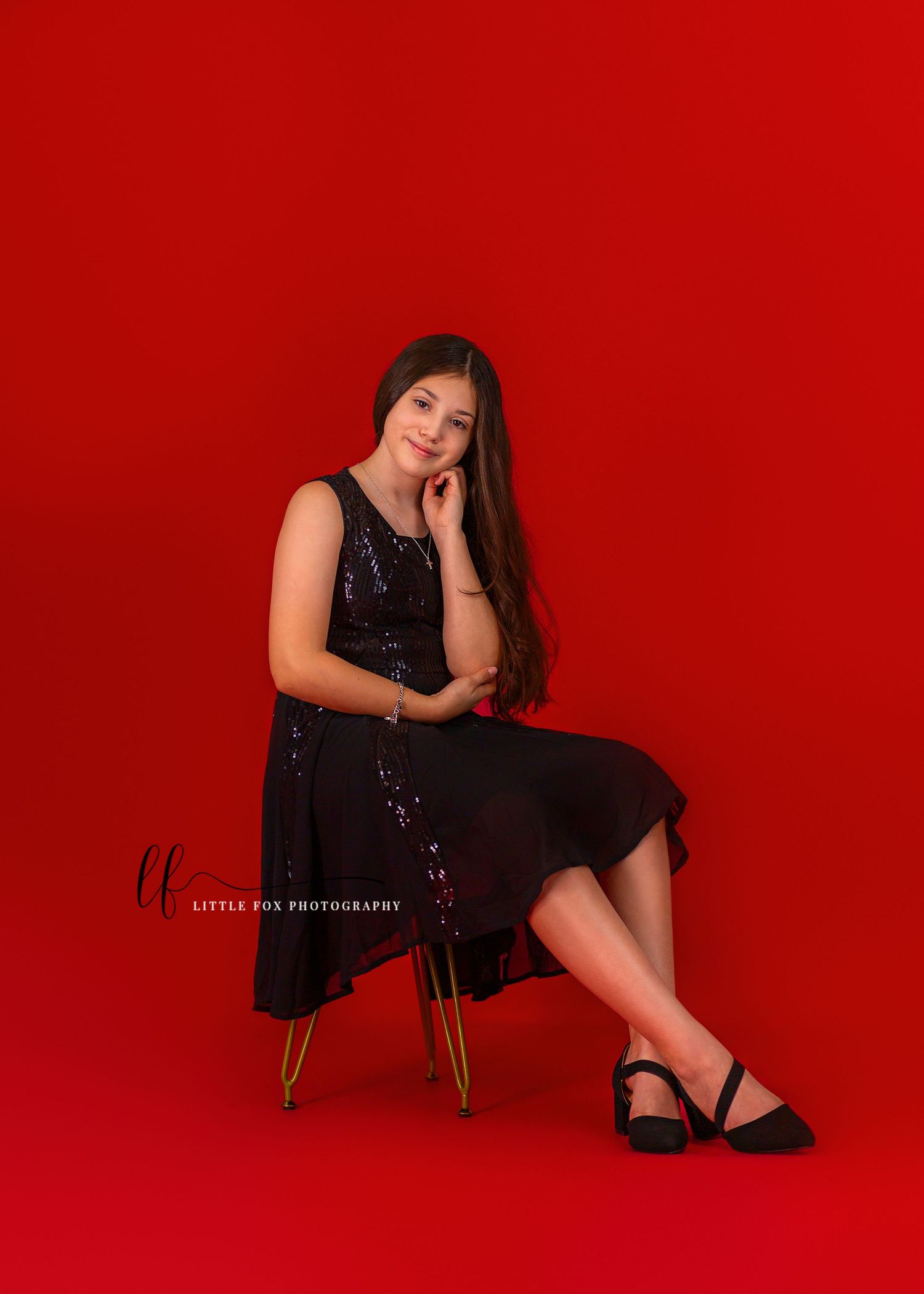 Little girl poses for portrait on red backdrop