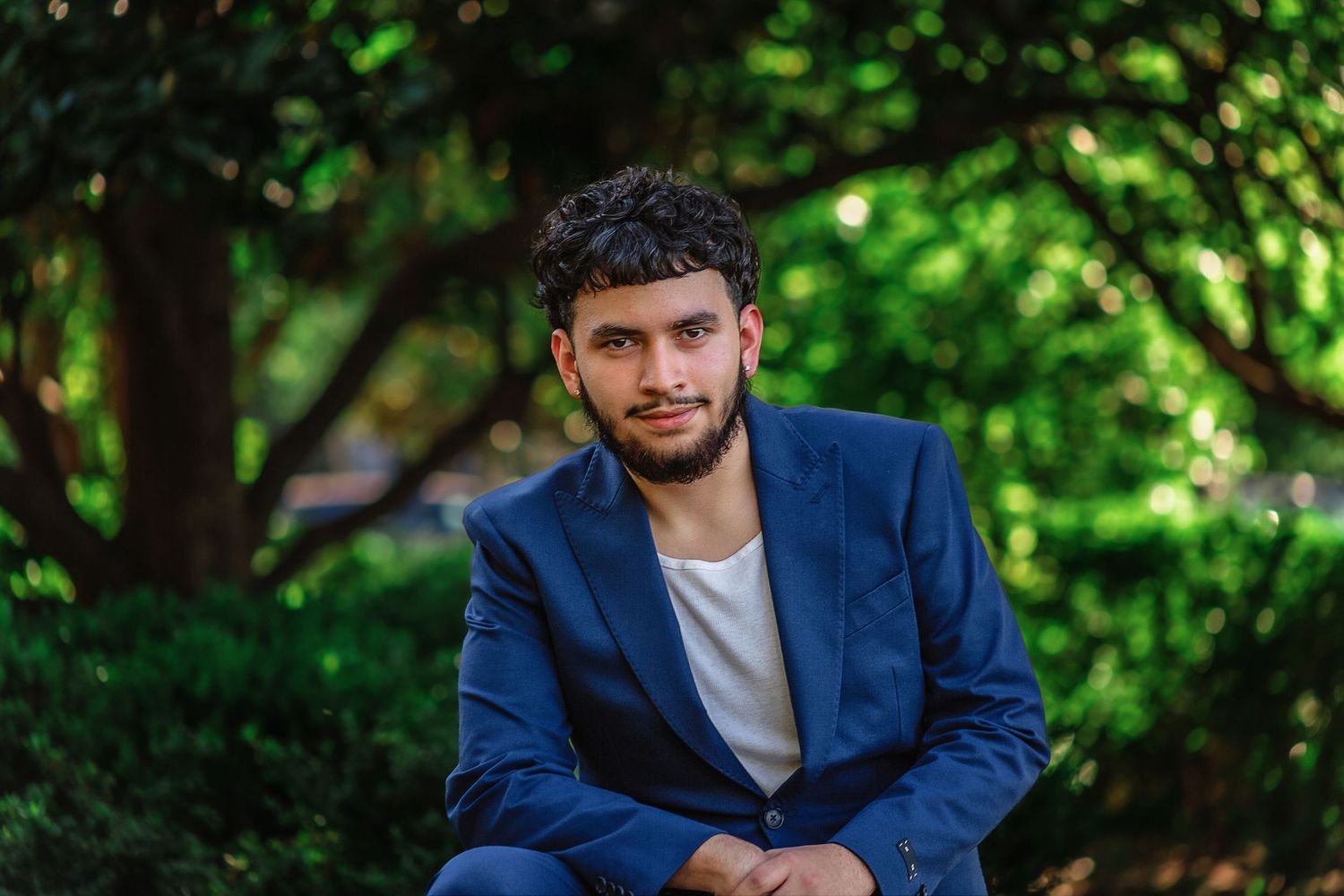 Senior boy posing outdoors with lush greenery background