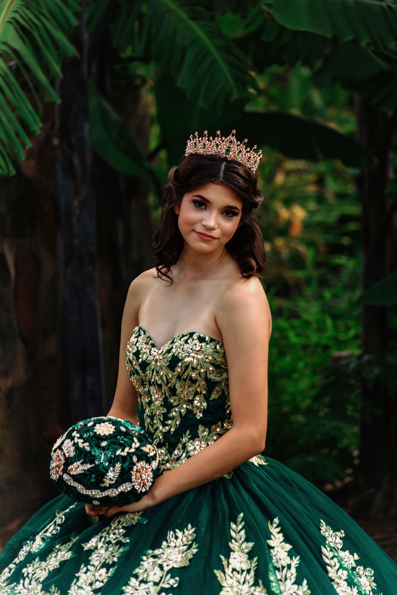 Outdoor Quinceañera photo of girl in elegant green and gold gown at park