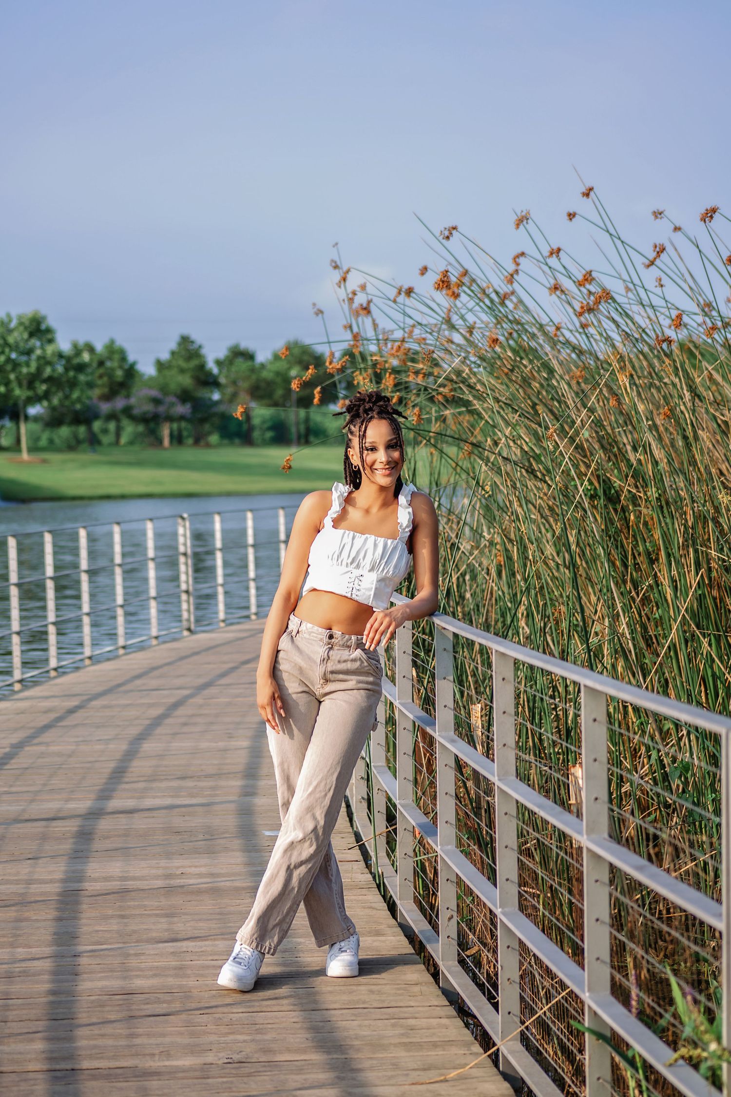 Senior girl leaning on metal railing on boardwalk for senior photoshoot