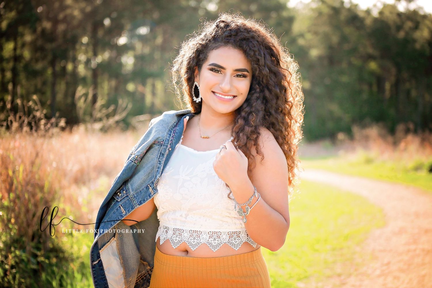 Backlit portrait of senior girl with denim jacket in open field