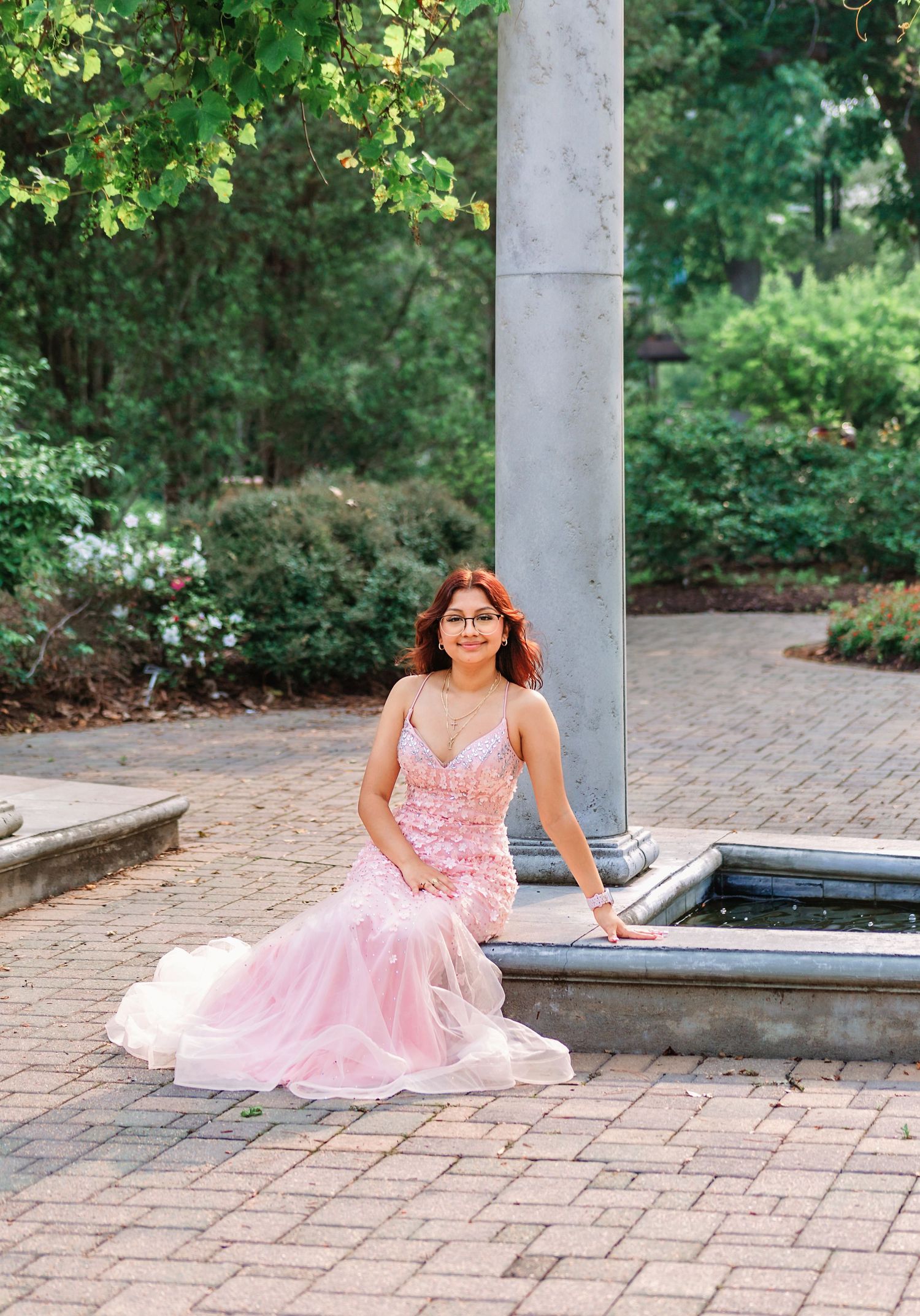 Portrait of senior girl in elegant pink prom dress with park background