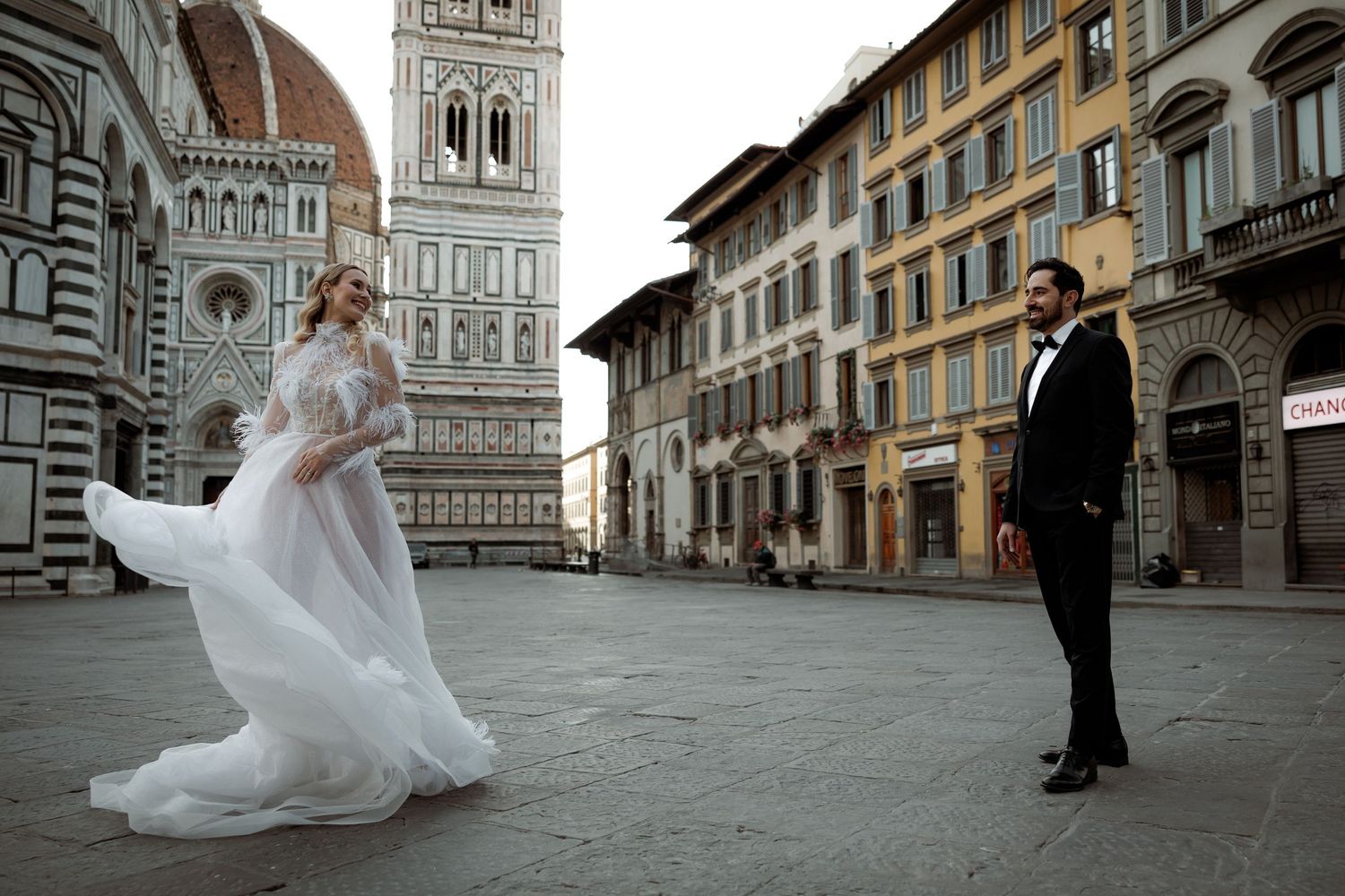 A couple in wedding attire poses in front of Florence's Duomo cathedral during a romantic photoshoot in Italy.