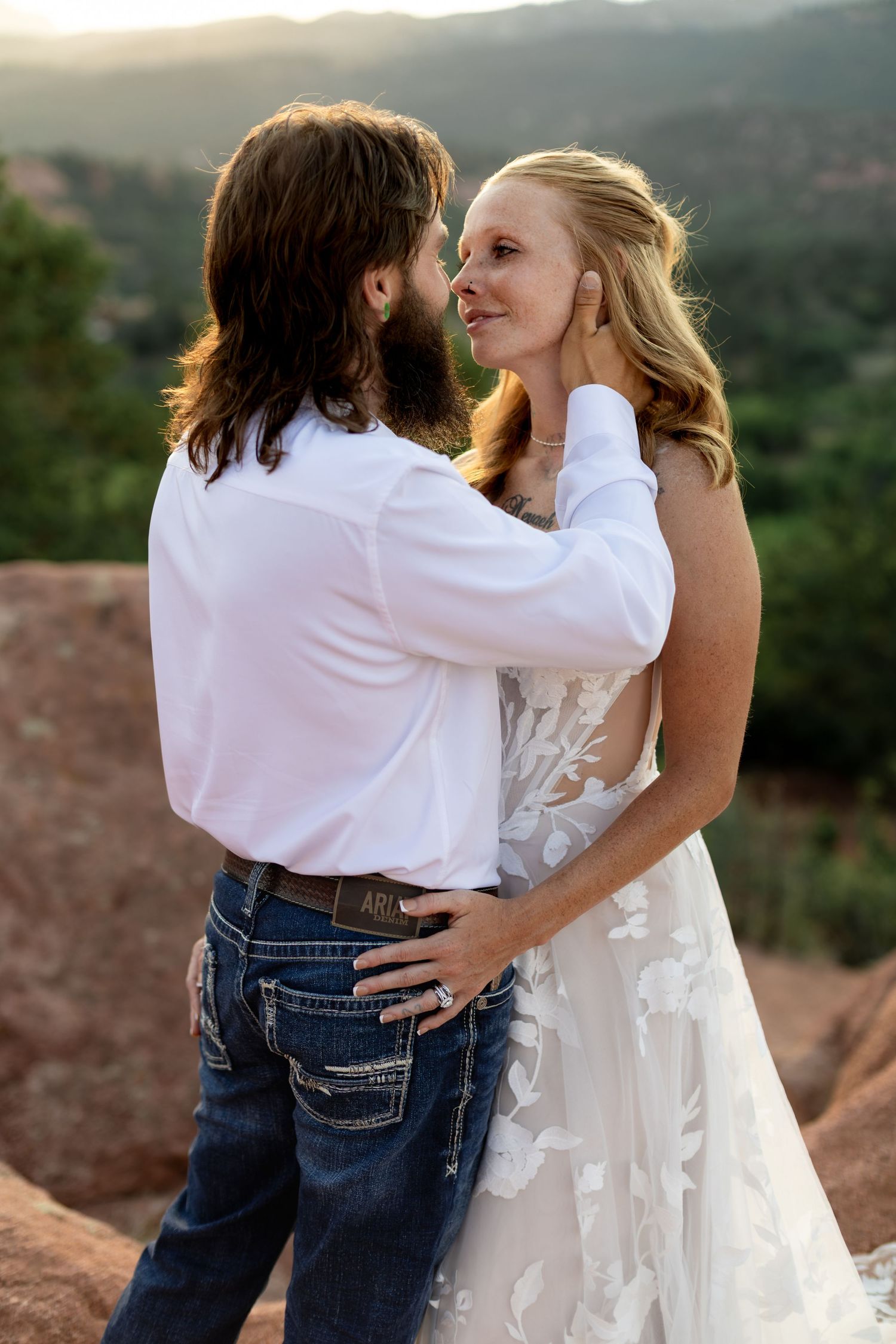 Bride and groom share romantic moment at sunset, groom gently cupping brides face at Garden of the Gods.