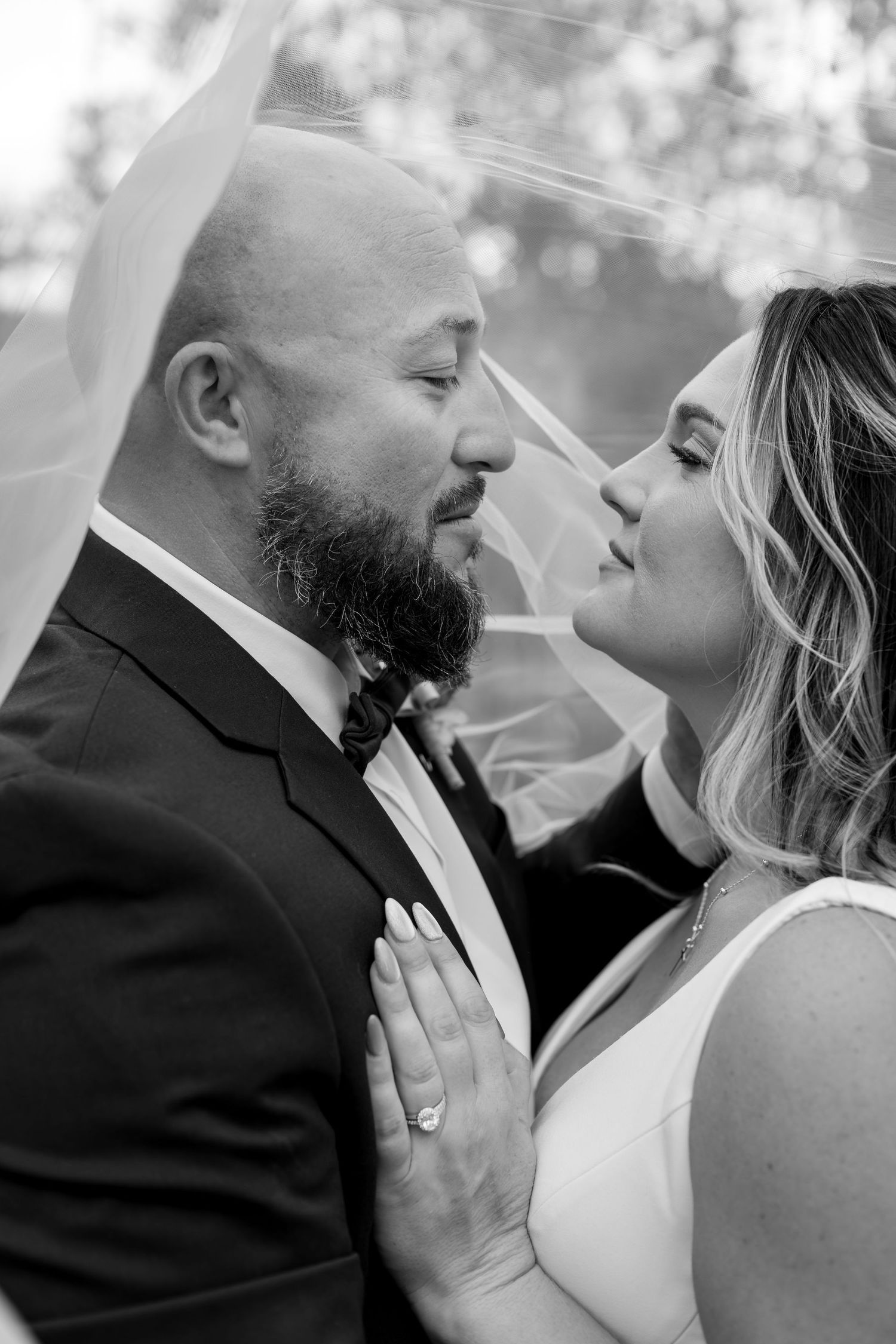 Black and white wedding photo of bride and groom sharing an intimate moment under a veil.
