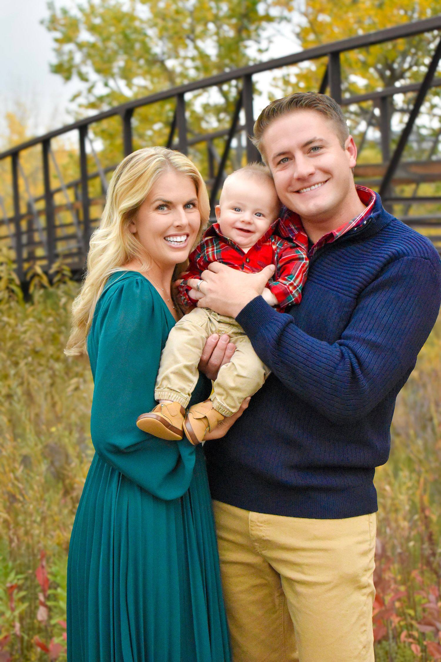 A family in coordinating outfits poses playfully against a backdrop of fall foliage.