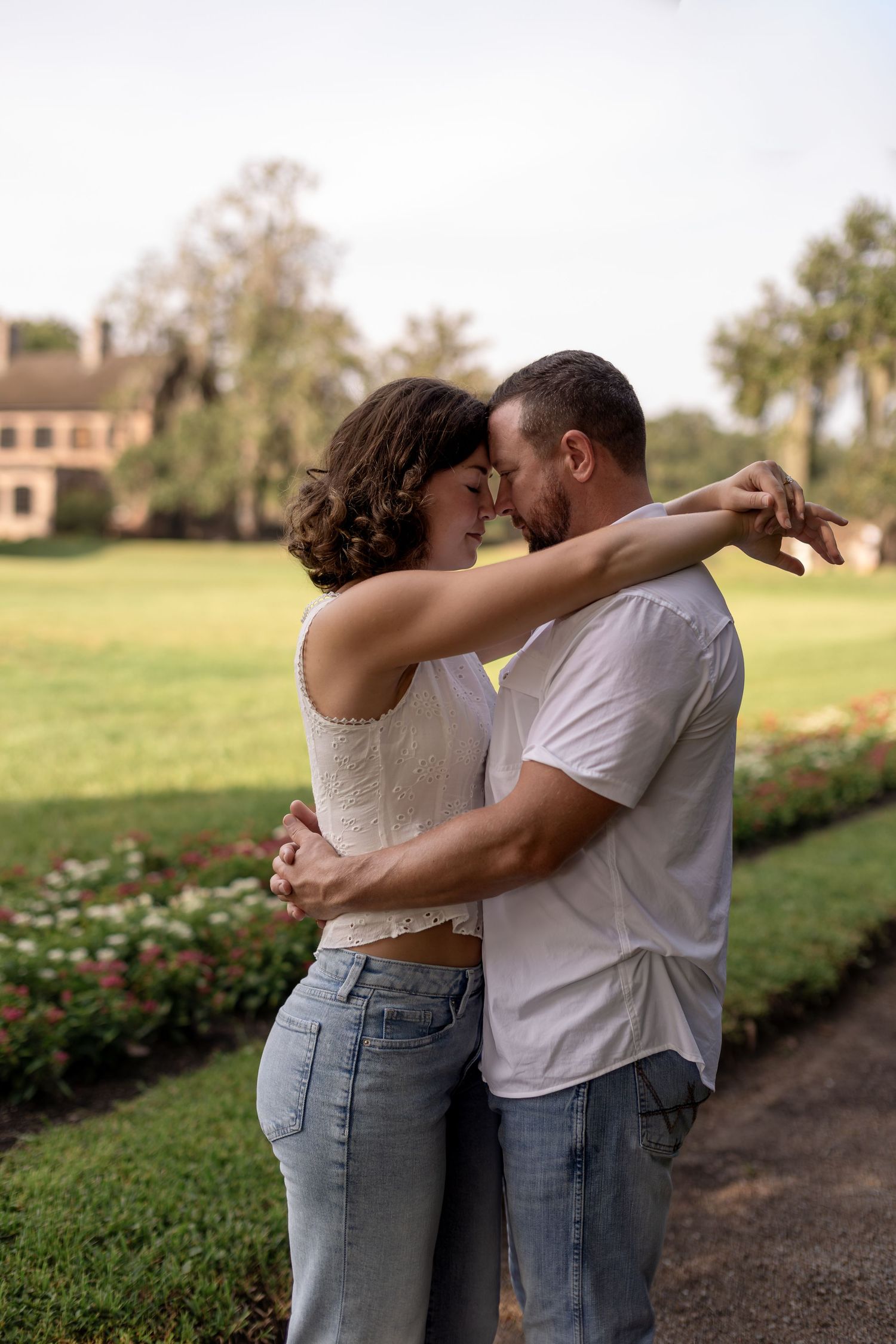 Couple embracing closely in a lush garden, foreheads touching romantically.
