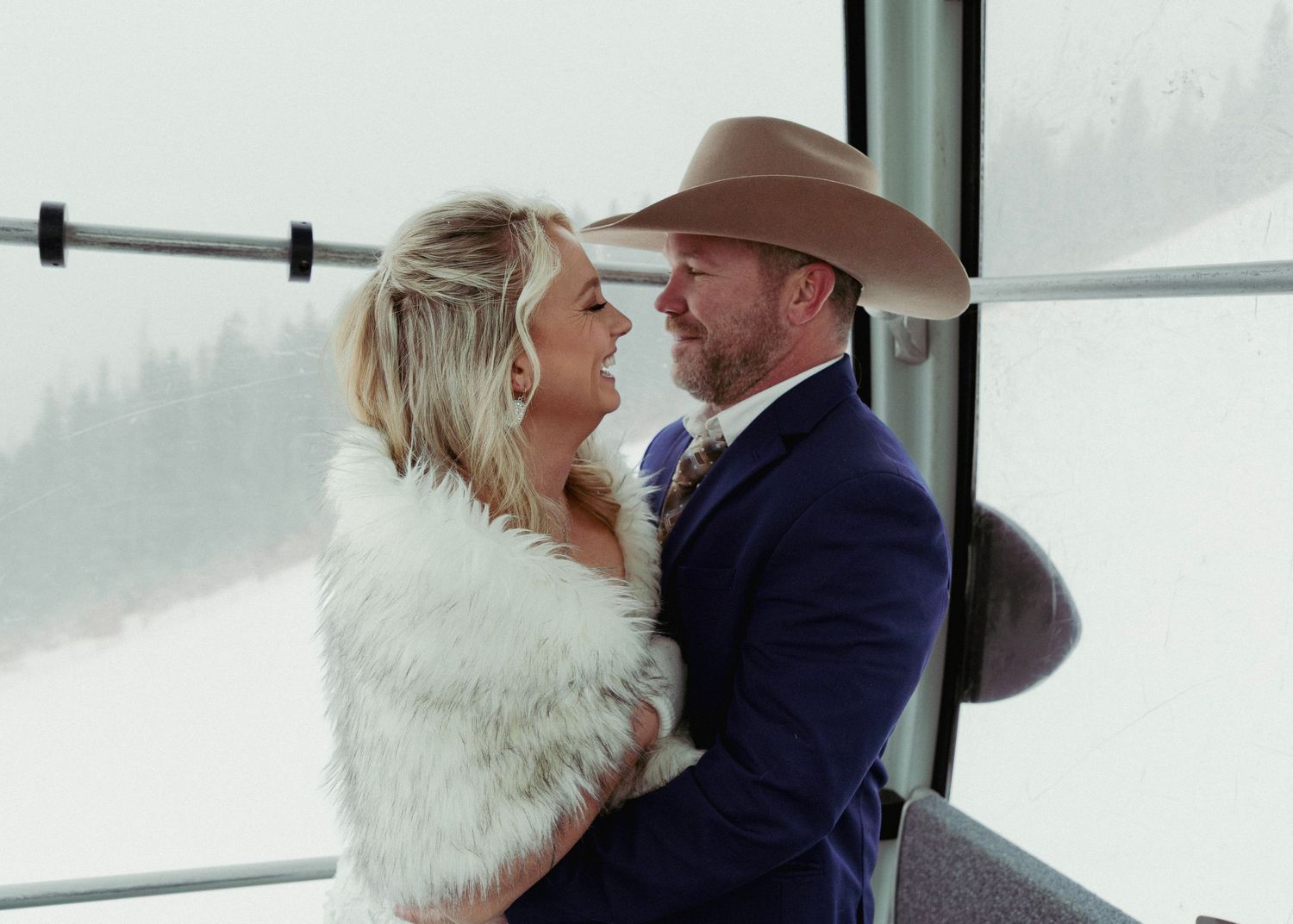 A couple shares a romantic moment in a winter setting with snow-covered mountains visible through large windows.
