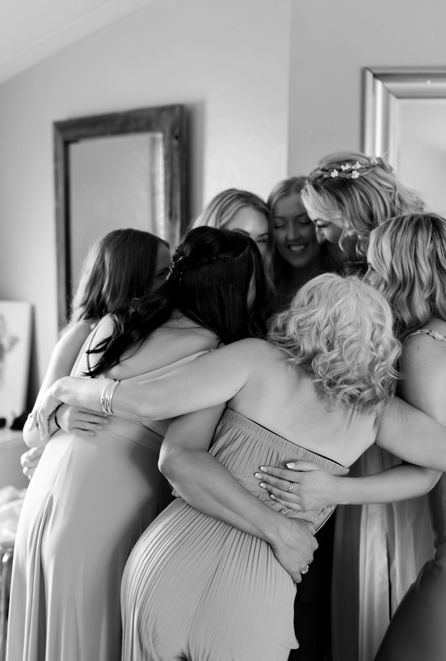 Bridesmaids share an emotional group hug with the bride while getting ready for the wedding.