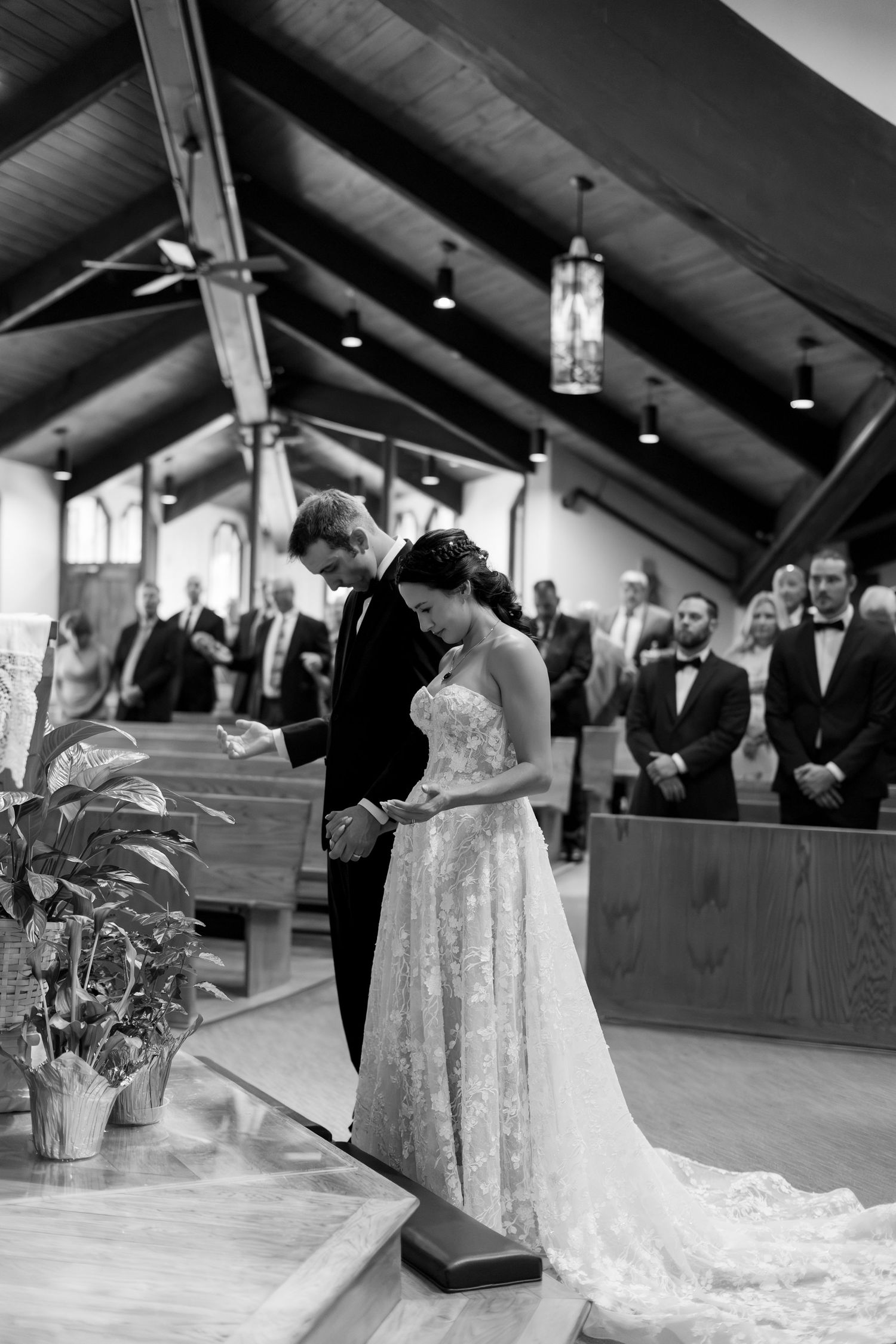 Black and white photo of bride and groom exchanging vows at church altar during elegant wedding ceremony.