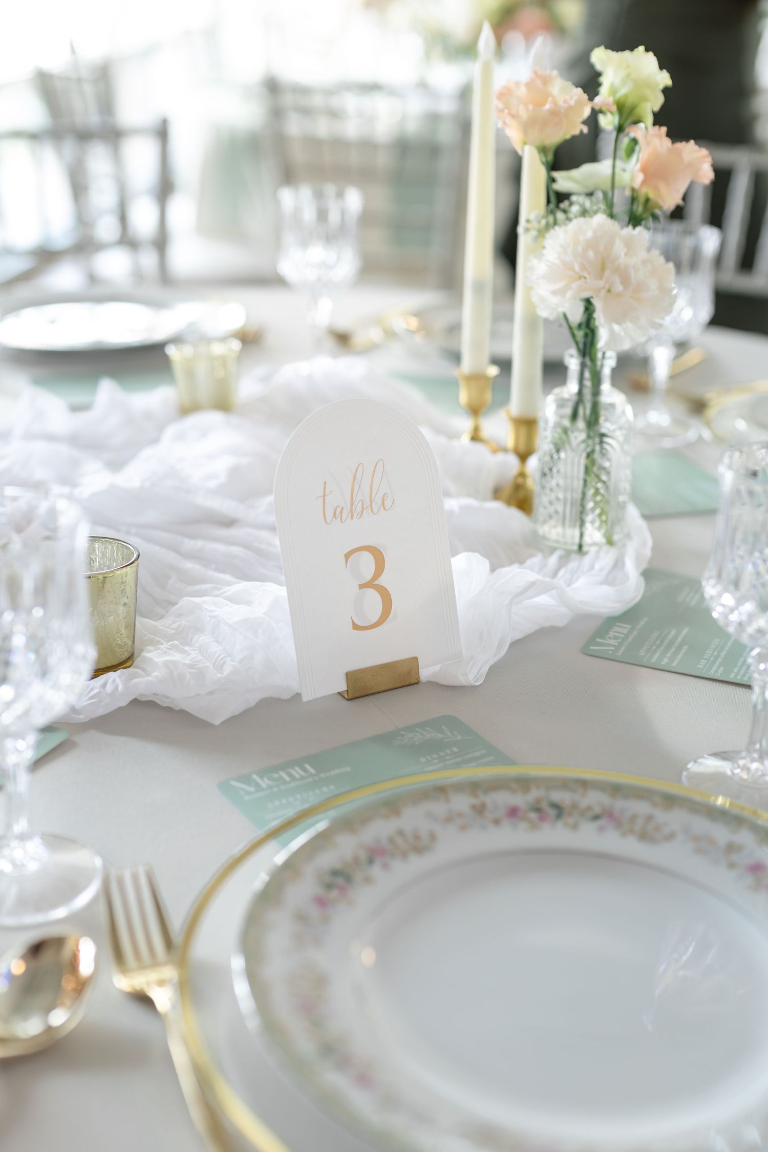 Elegant wedding reception table setting with Table 3 card, gold accents, vintage china, and soft floral arrangements.